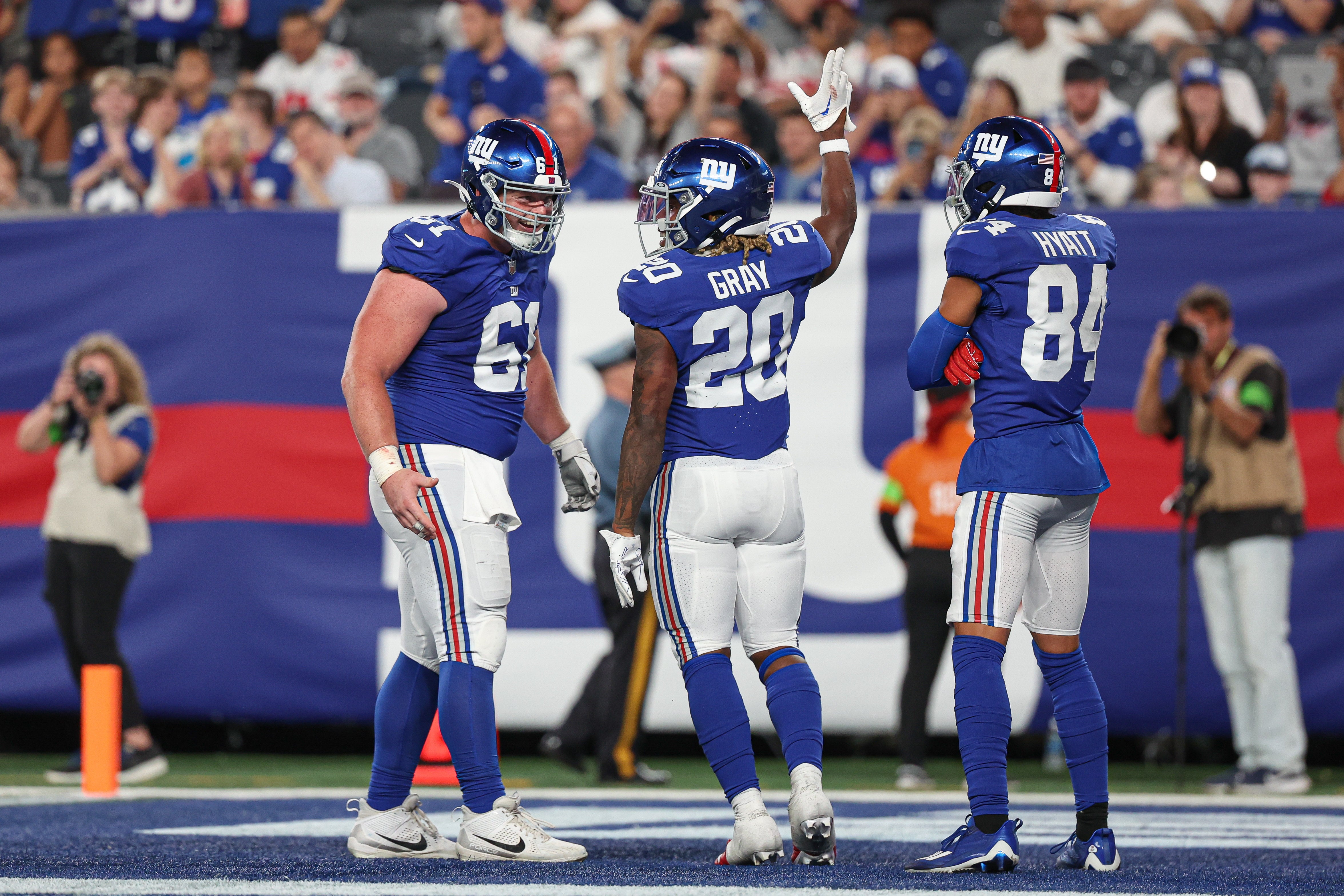 Aug 18, 2023; East Rutherford, New Jersey, USA; New York Giants running back Eric Gray (20) celebrates his rushing touchdown with center John Michael Schmitz Jr. (61) and wide receiver Jalin Hyatt (84) during the first half against the Carolina Panthers at MetLife Stadium. Mandatory Credit: Vincent Carchietta-USA TODAY Sports