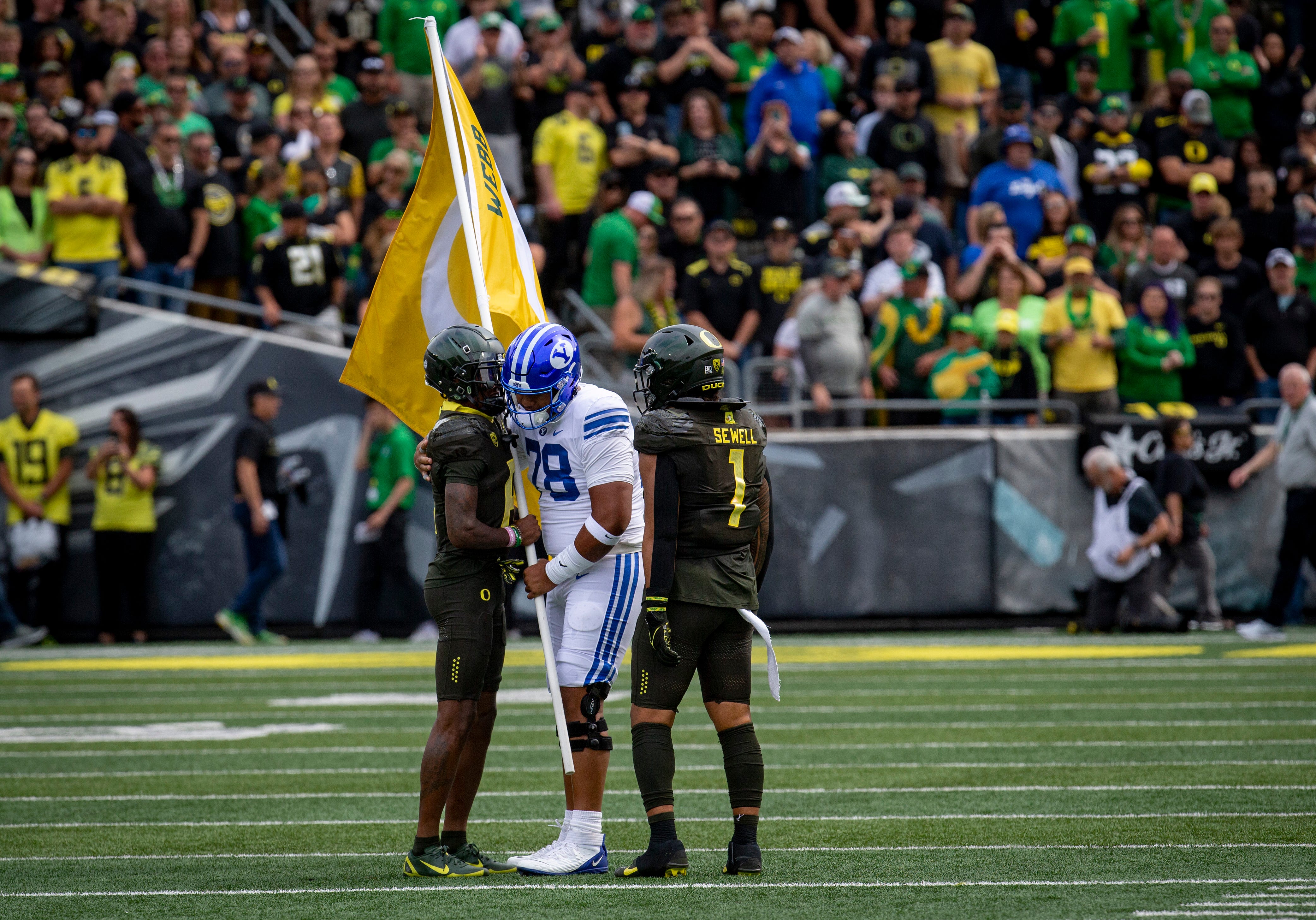 BYU offensive lineman Kingsley Suamataia hands off a flag honoring Oregon's Spencer Webb to Oregon wide receiver Isaah Crocker before the start of a Saturday, Sept. 17, 2022, game at Autzen Stadium. Mandatory Credit: Ben Lonergan/The Register-Guard / USA TODAY NETWORK