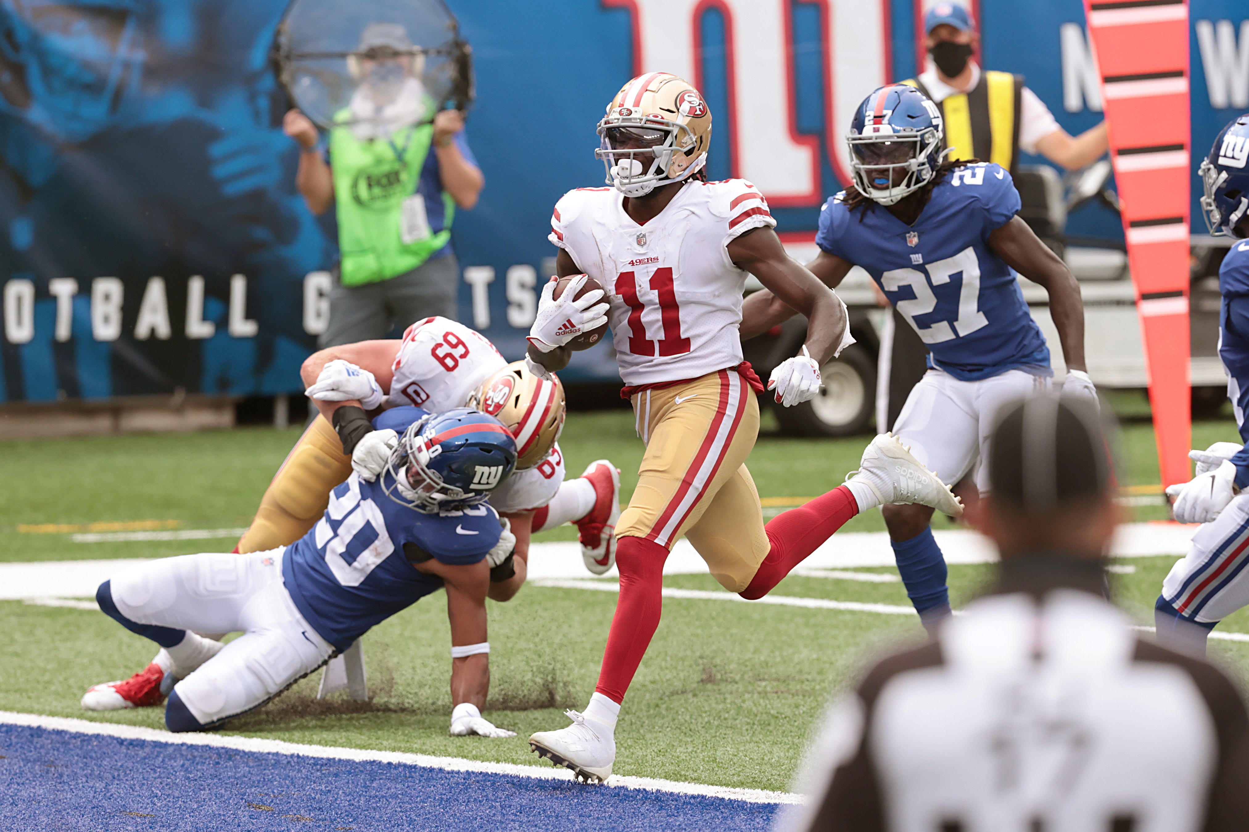 Sep 27, 2020; East Rutherford, New Jersey, USA; San Francisco 49ers wide receiver Brandon Aiyuk (11) scores a touchdown during the second half in front of New York Giants free safety Julian Love (20) and cornerback Isaac Yiadom (27) at MetLife Stadium. Mandatory Credit: Vincent Carchietta-USA TODAY Sports