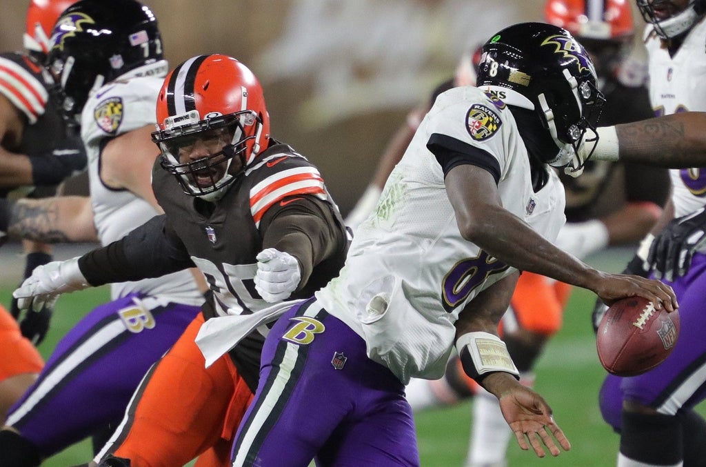 Baltimore Ravens quarterback Lamar Jackson (8) narrowly escapes Cleveland Browns defensive end Myles Garrett (95) as he scrambles for yards during the first half of an NFL football game, Monday, Dec. 14, 2020, in Cleveland, Ohio.