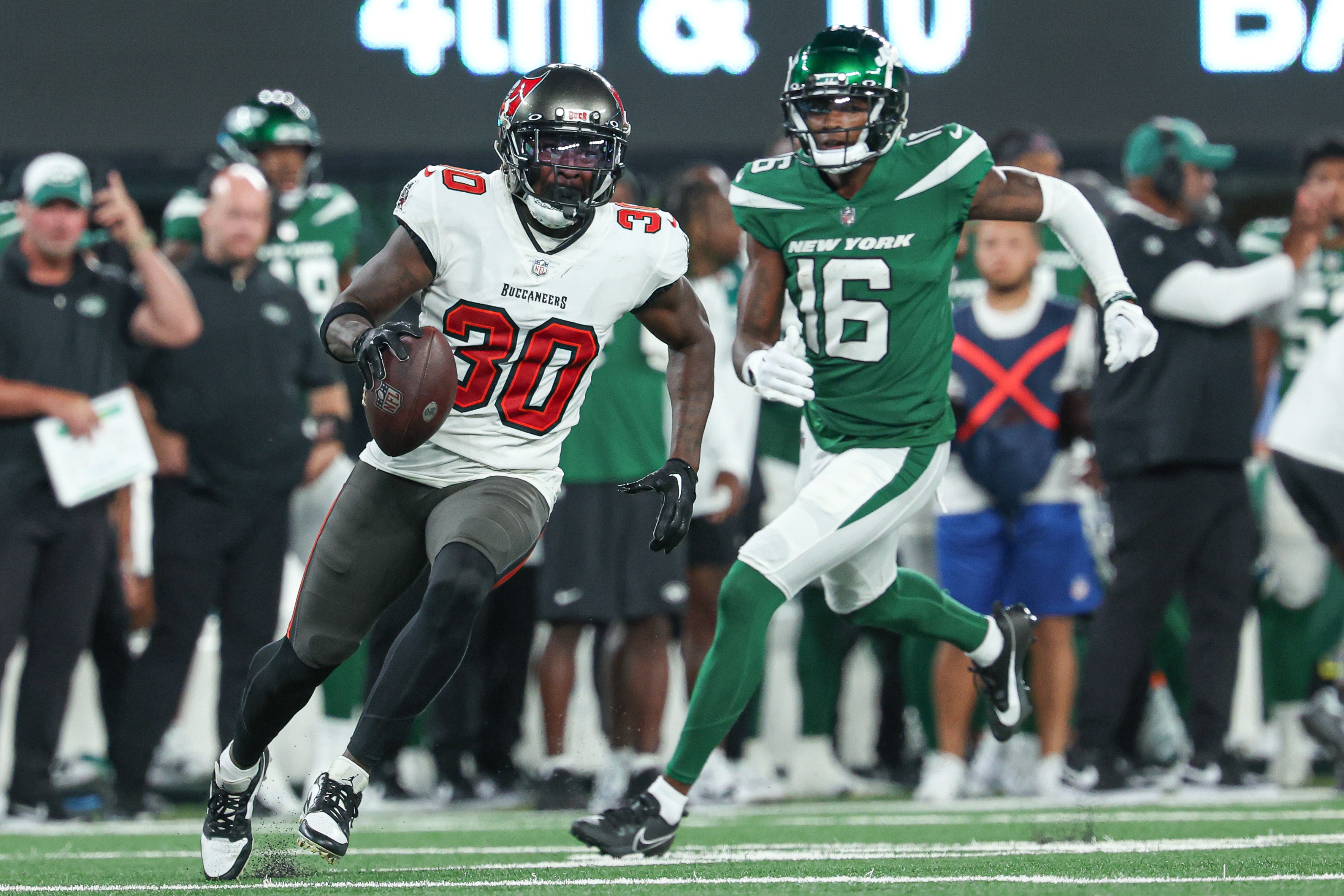 Aug 19, 2023; East Rutherford, New Jersey, USA; Tampa Bay Buccaneers cornerback Dee Delaney (30) runs with the ball after an interception in front of New York Jets wide receiver Jason Brownlee (16) during the second half at MetLife Stadium. Mandatory Credit: Vincent Carchietta-USA TODAY Sports