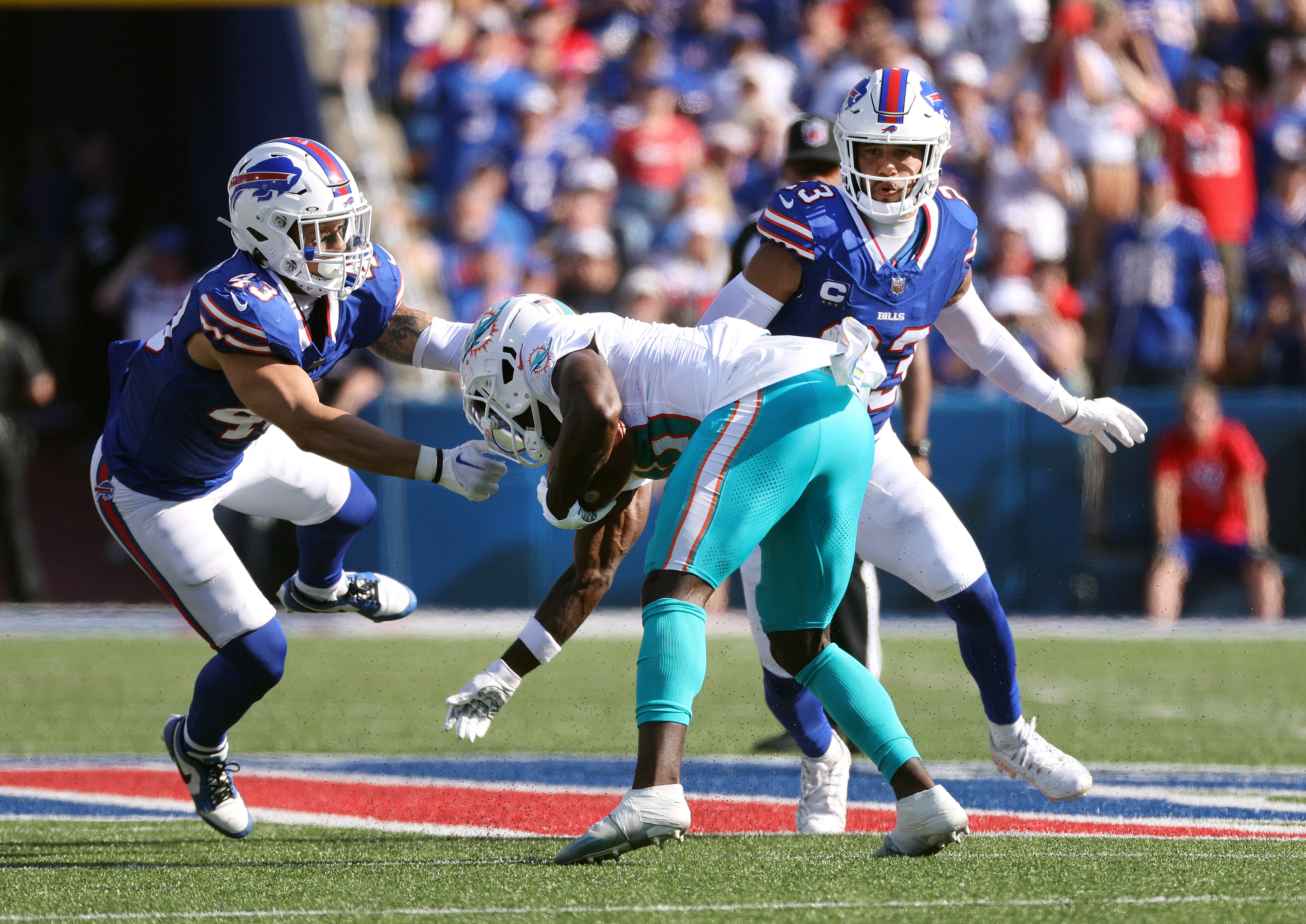 Miami Dolphins WR Tyreek Hill being tackled by LB Terrel Bernard and S Micah Hyde