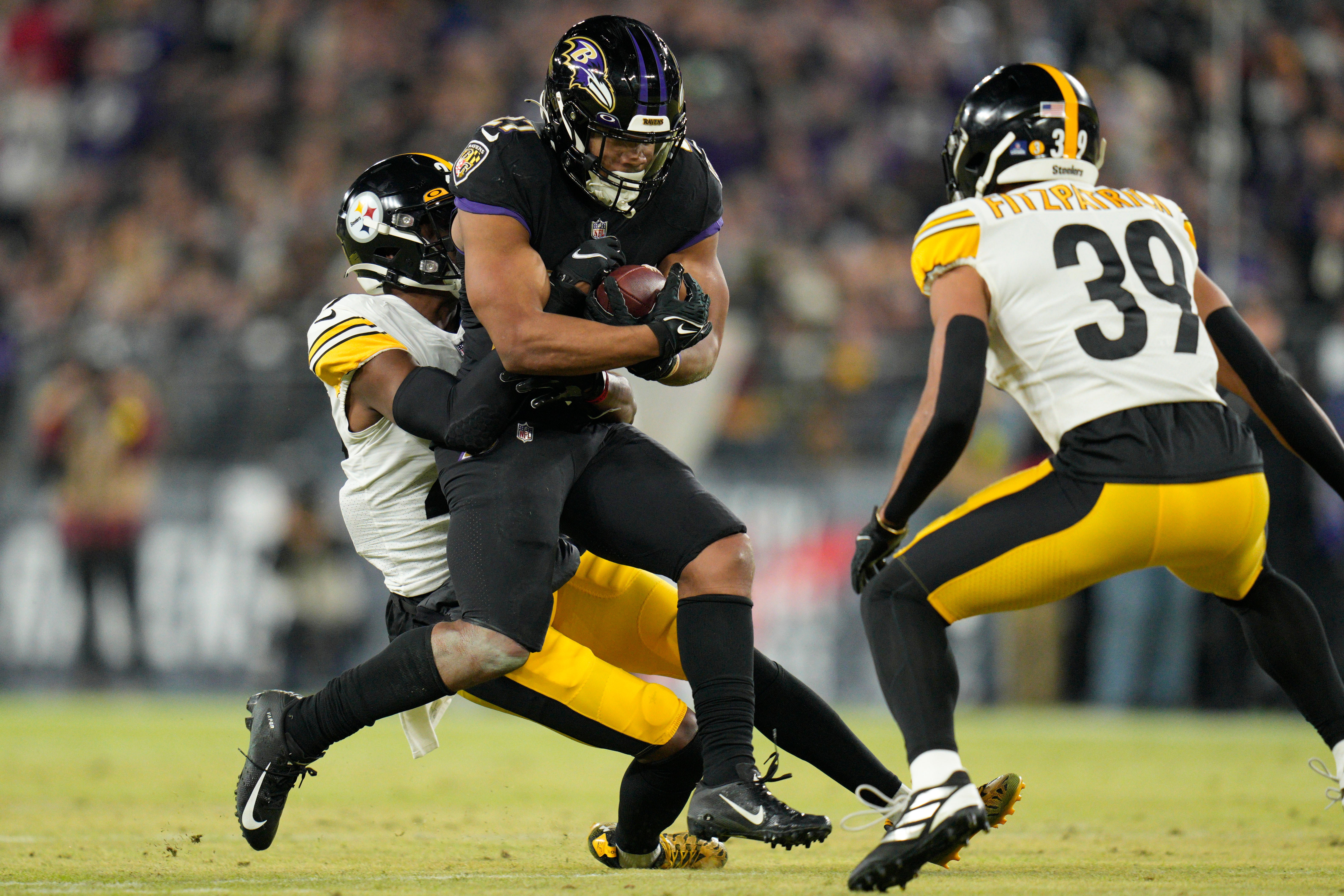 Jan 1, 2023; Baltimore, Maryland, USA; Baltimore Ravens running back J.K. Dobbins (27) runs as Pittsburgh Steelers cornerback Levi Wallace (29) and safety Minkah Fitzpatrick (39) defend during the first half at M&T Bank Stadium. Mandatory Credit: Jessica Rapfogel-USA TODAY Sports  