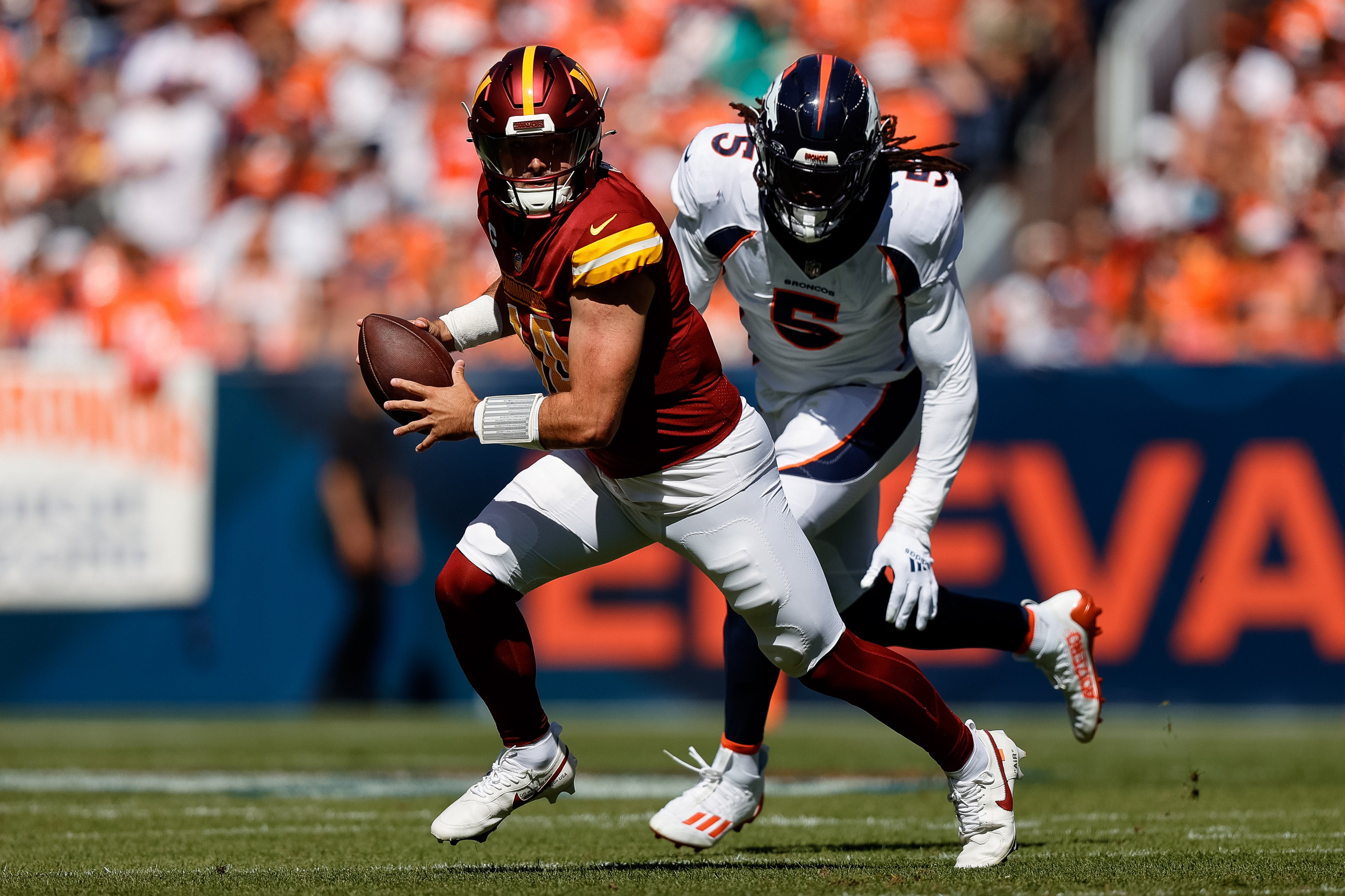 Sep 17, 2023; Denver, Colorado, USA; Washington Commanders quarterback Sam Howell (14) scrambles under pressure from Denver Broncos linebacker Randy Gregory (5) in the first quarter at Empower Field at Mile High.
