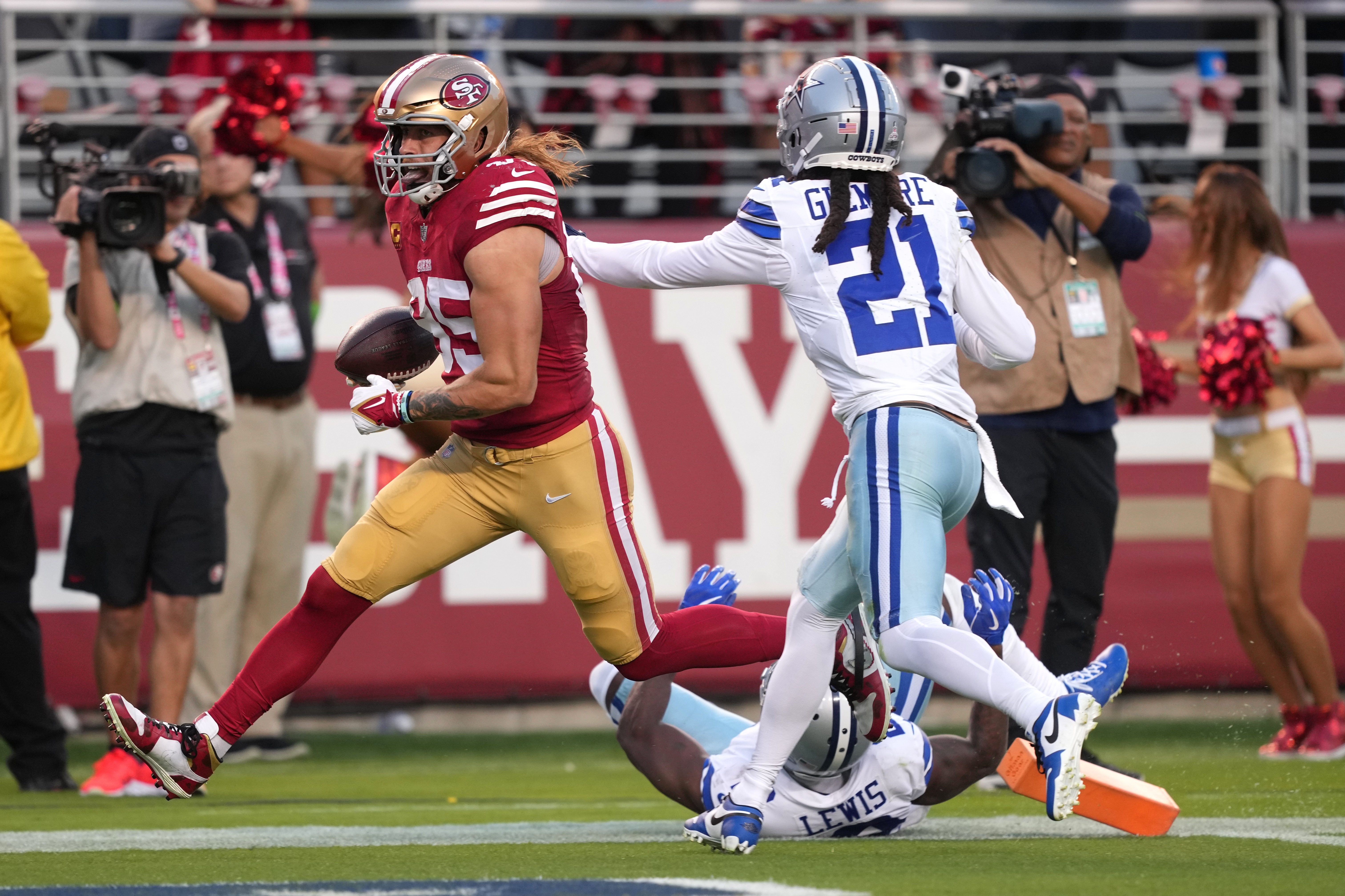 Oct 8, 2023; Santa Clara, California, USA; San Francisco 49ers tight end George Kittle (85) scores a touchdown against Dallas Cowboys cornerback Stephon Gilmore (21) and cornerback Jourdan Lewis (on ground) during the second quarter at Levi's Stadium.