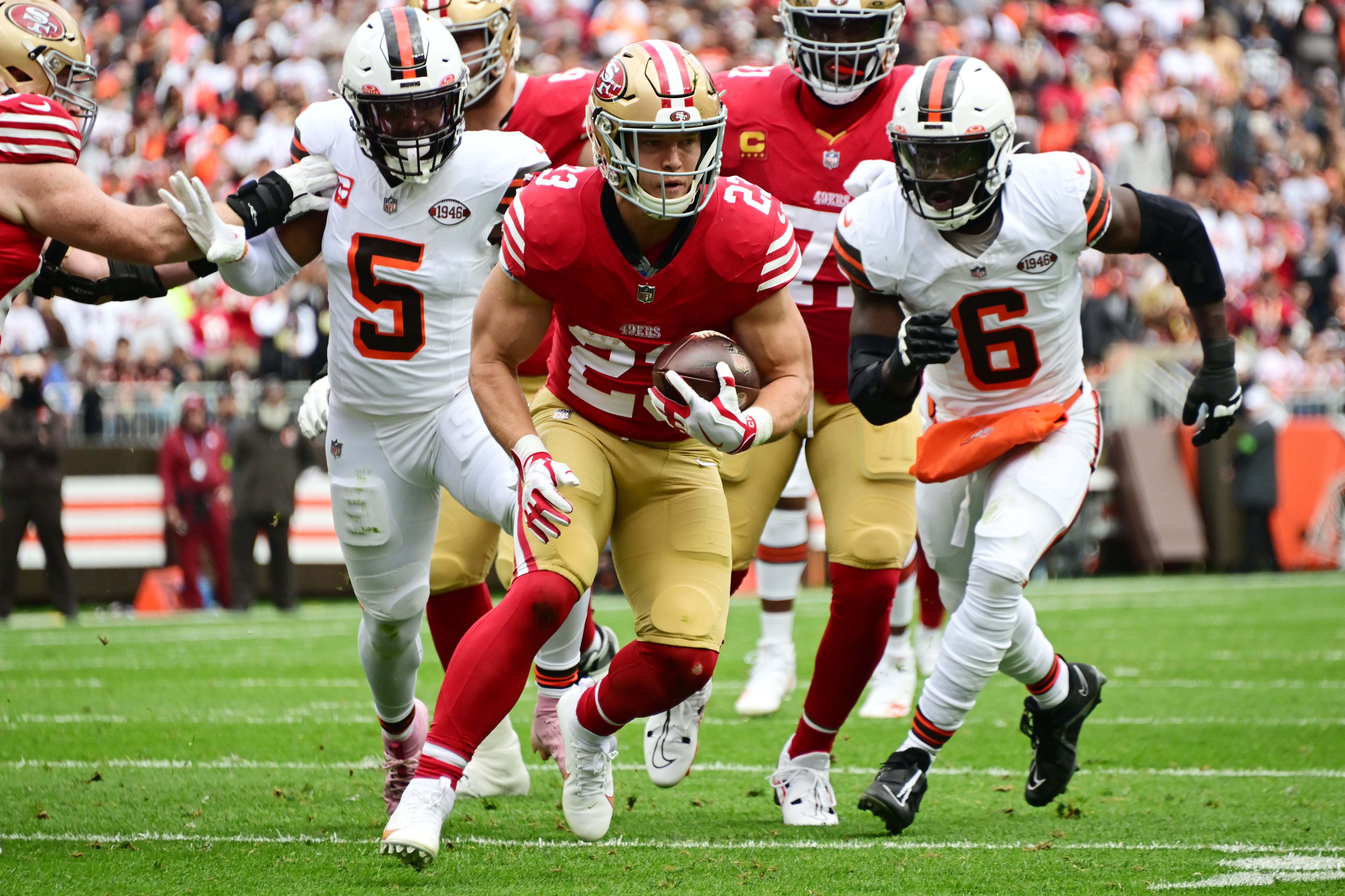 Oct 15, 2023; Cleveland, Ohio, USA; San Francisco 49ers running back Christian McCaffrey (23) runs with the ball en route to a touchdown as Cleveland Browns linebacker Anthony Walker Jr. (5) and linebacker Jeremiah Owusu-Koramoah (6) pursue during the first half at Cleveland Browns Stadium.