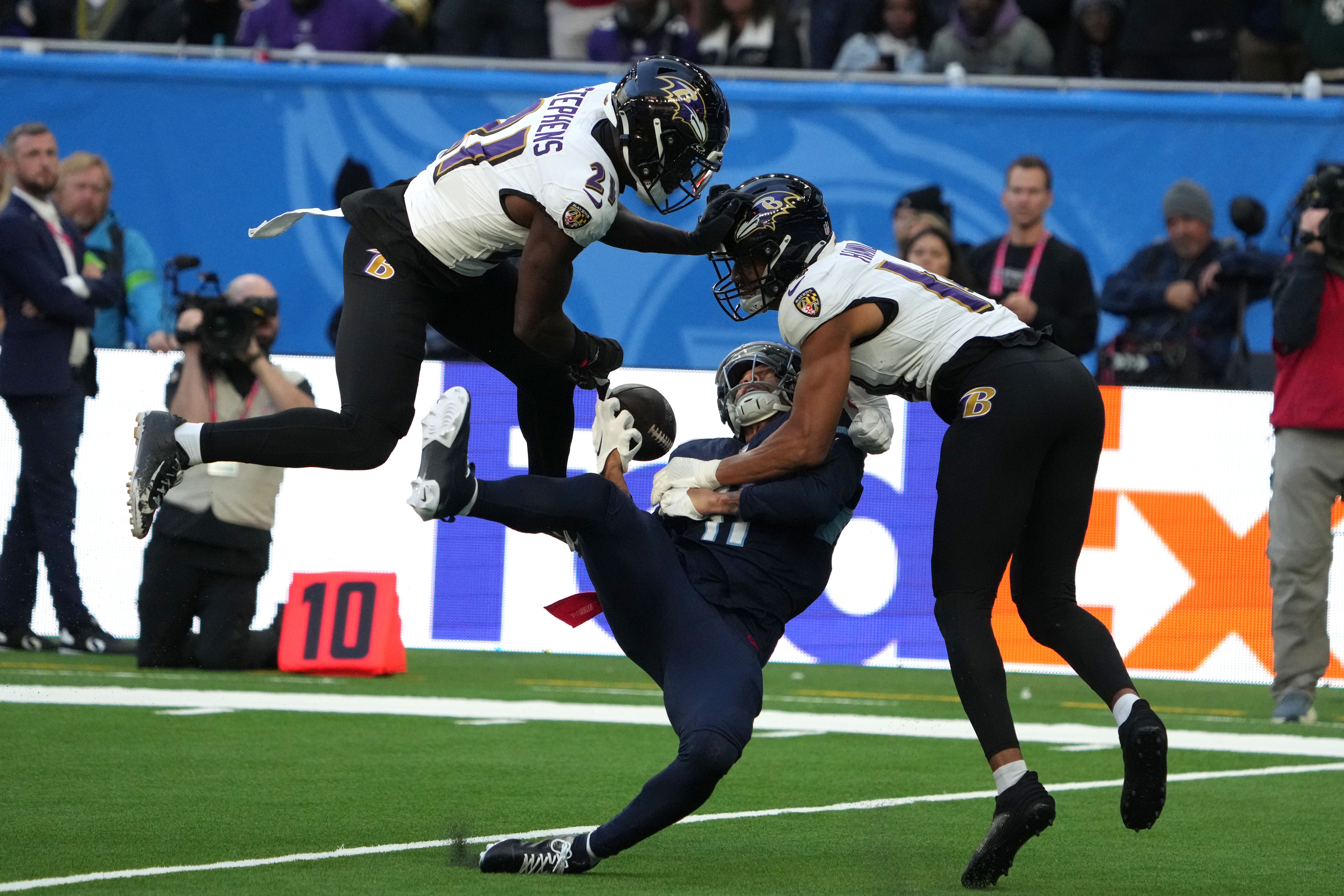Tennessee Titans wide receiver Chris Moore (11) attempts to catch the ball against Baltimore Ravens cornerback Brandon Stephens (21) and safety Kyle Hamilton (14) in the second half during an NFL International Series game at Tottenham Hotspur Stadium.
