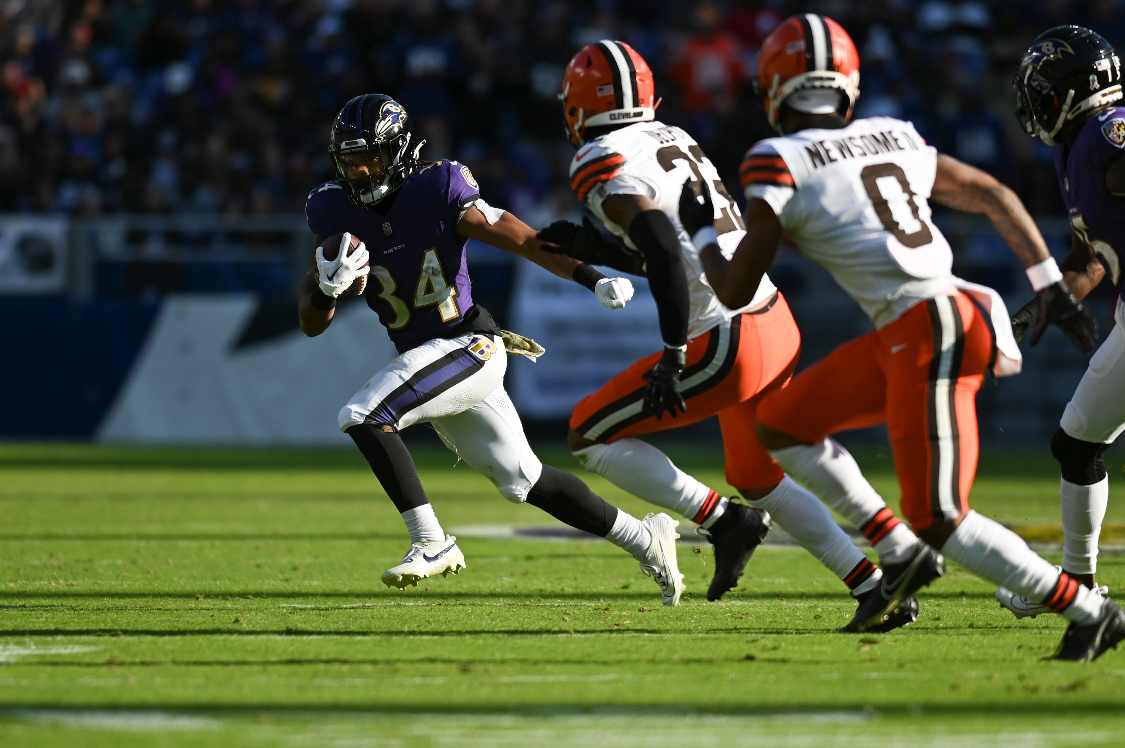 Baltimore Ravens running back Keaton Mitchell (34) rehashes a Cleveland Browns cornerback Martin Emerson Jr. (23) defends during the first half at M&T Bank Stadium.