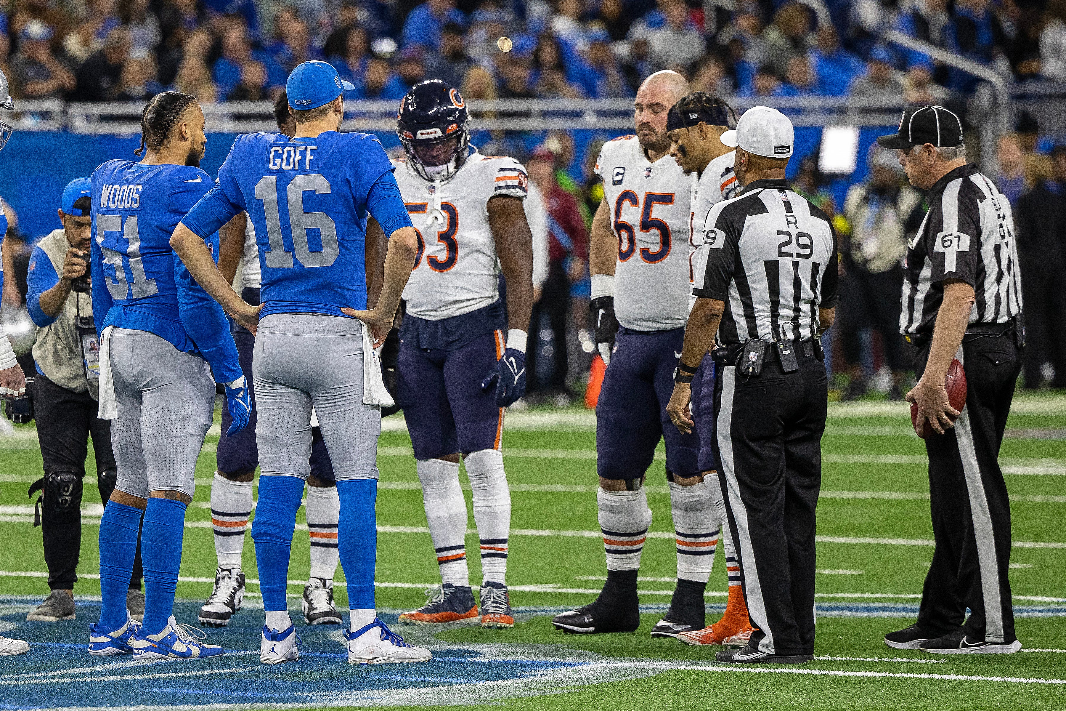 Jan 1, 2023; Detroit, Michigan, USA; referee Adrian Hill (29) tossed the coin in the air between Detroit Lions quarterback Jared Goff (16) and Chicago Bears center Cody Whitehair (65) before the start of the game at Ford Field. Mandatory Credit: