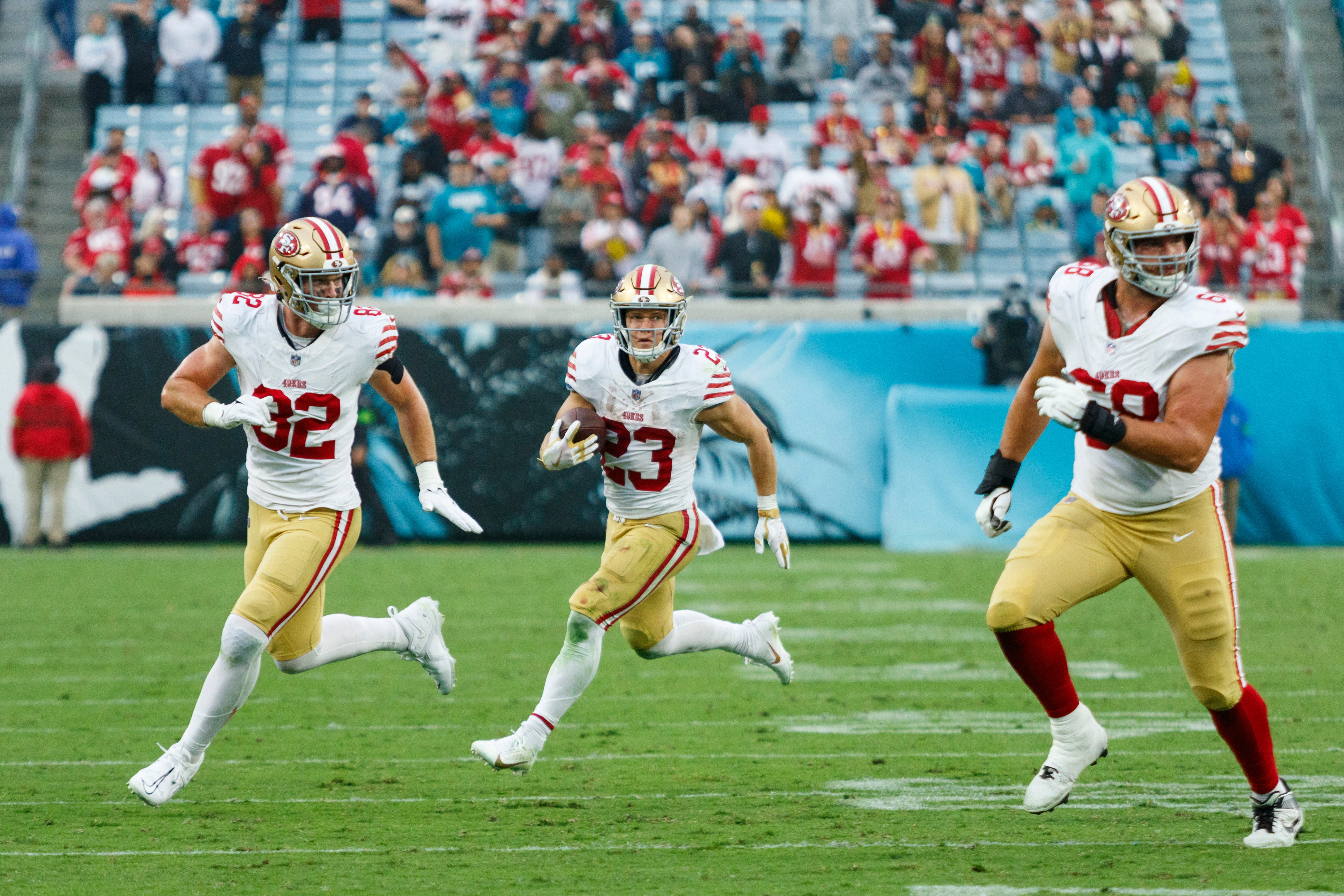 Nov 12, 2023; Jacksonville, Florida, USA; San Francisco 49ers running back Christian McCaffrey (23) carries the ball with running back Tyrion Davis-Price (32) and offensive tackle Colton McKivitz (68) running alongside during the fourth quarter at EverBank Stadium.