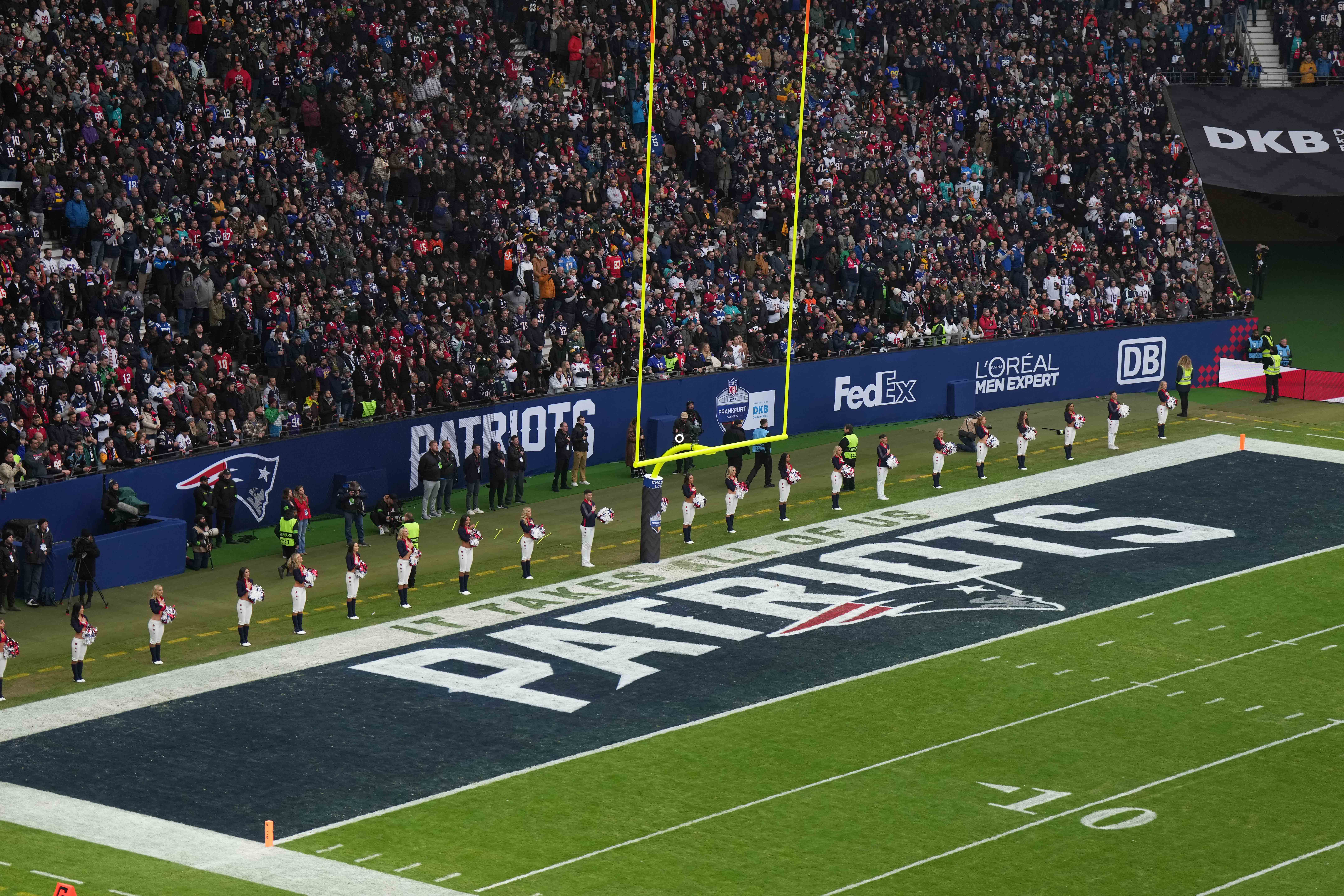 New England Patriots cheerleaders observe the playing of the national anthem in the end zone with a Patriots logo during an NFL International Series game against the Indianapolis Colts at Deutsche Bank Park