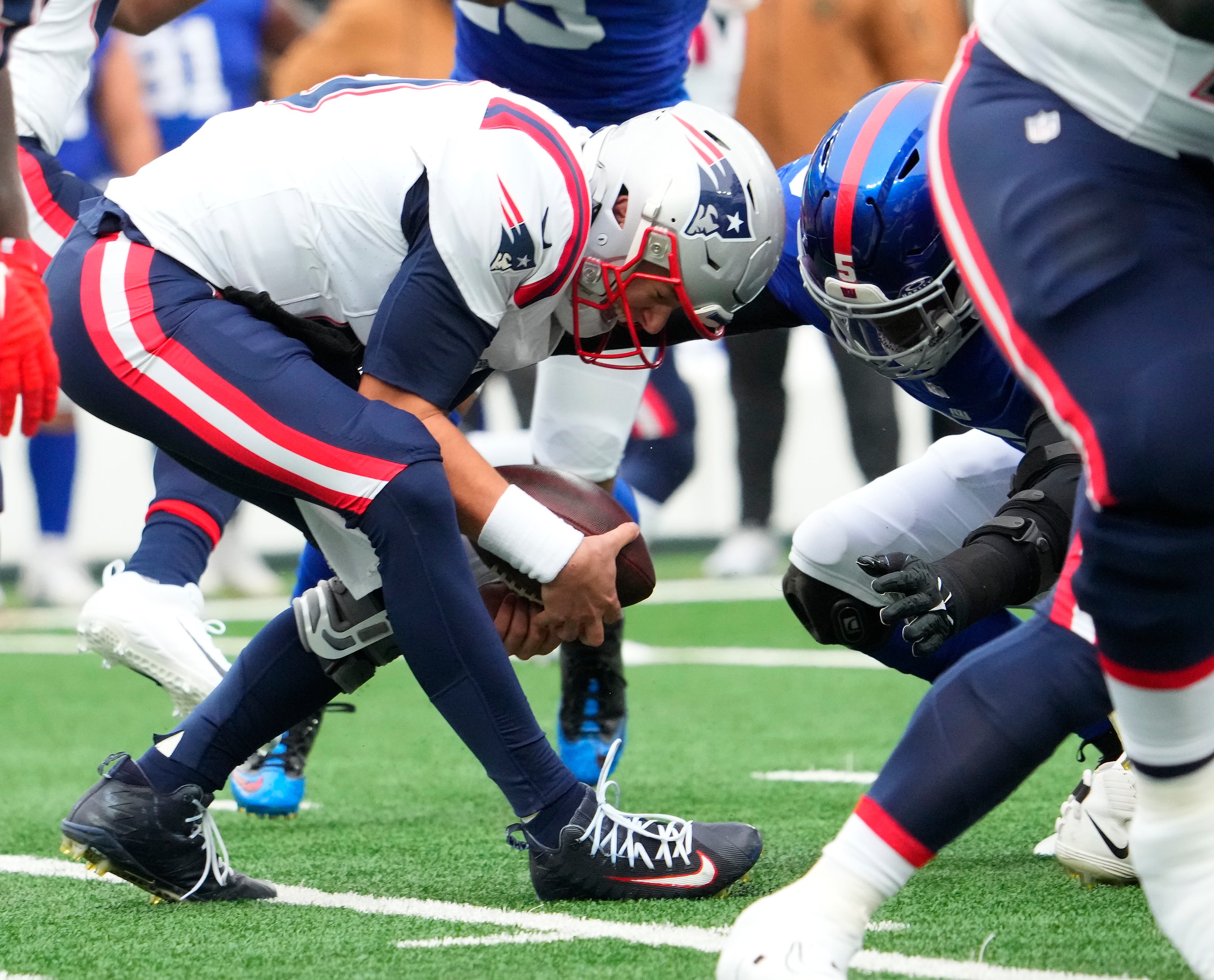New England Patriots quarterback Mac Jones grabs a bad snap as New York Giants linebacker Kayvon Thibodeaux (5) closes in in the 1st quarter at MetLife Stadium