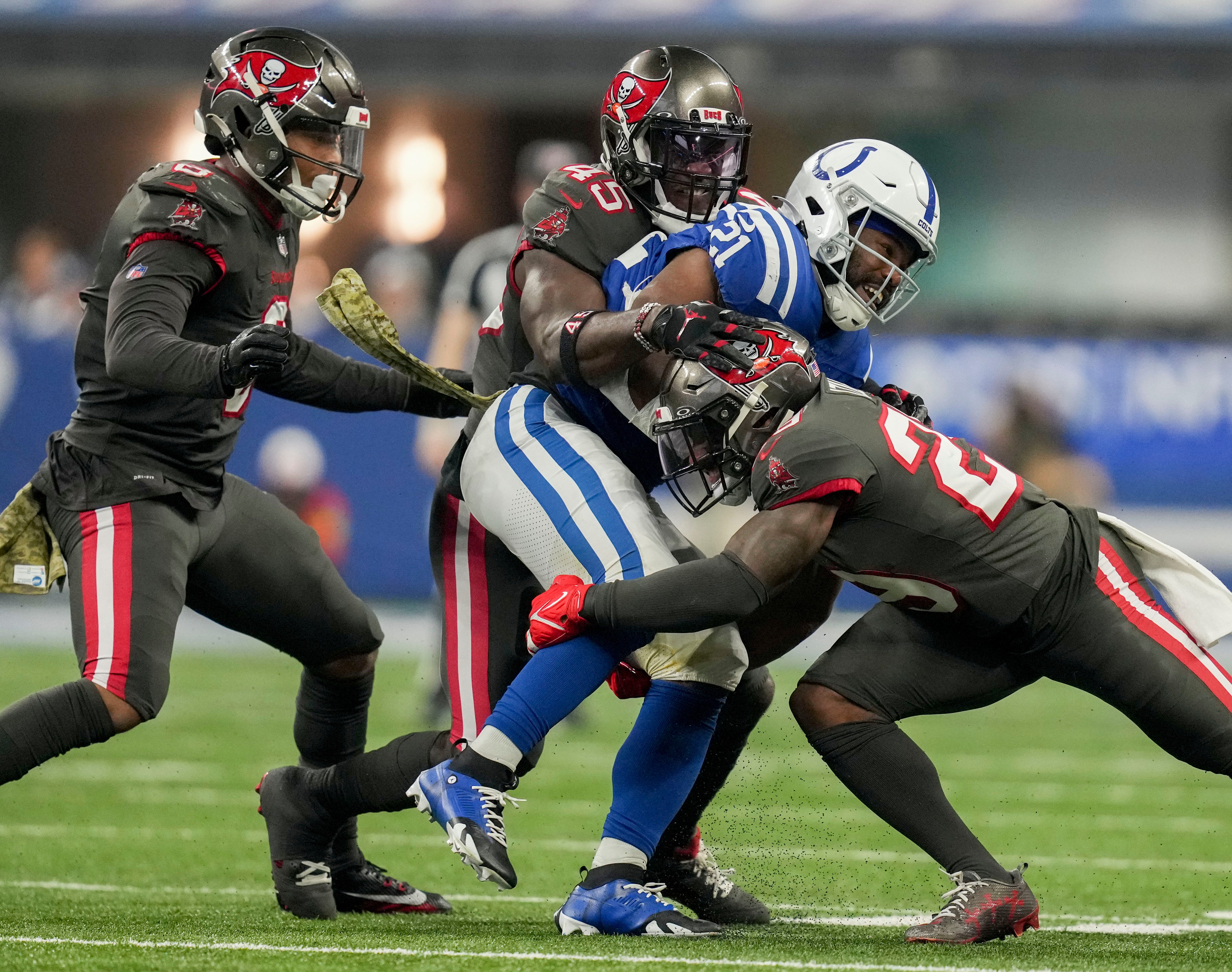 Tampa Bay Buccaneers linebacker Devin White (45) and Tampa Bay Buccaneers safety Christian Izien (29) work to bring down Indianapolis Colts running back Zack Moss (21) on Sunday, Nov. 26, 2023, during a game against the Tampa Bay Buccaneers at Lucas Oil Stadium in Indianapolis.