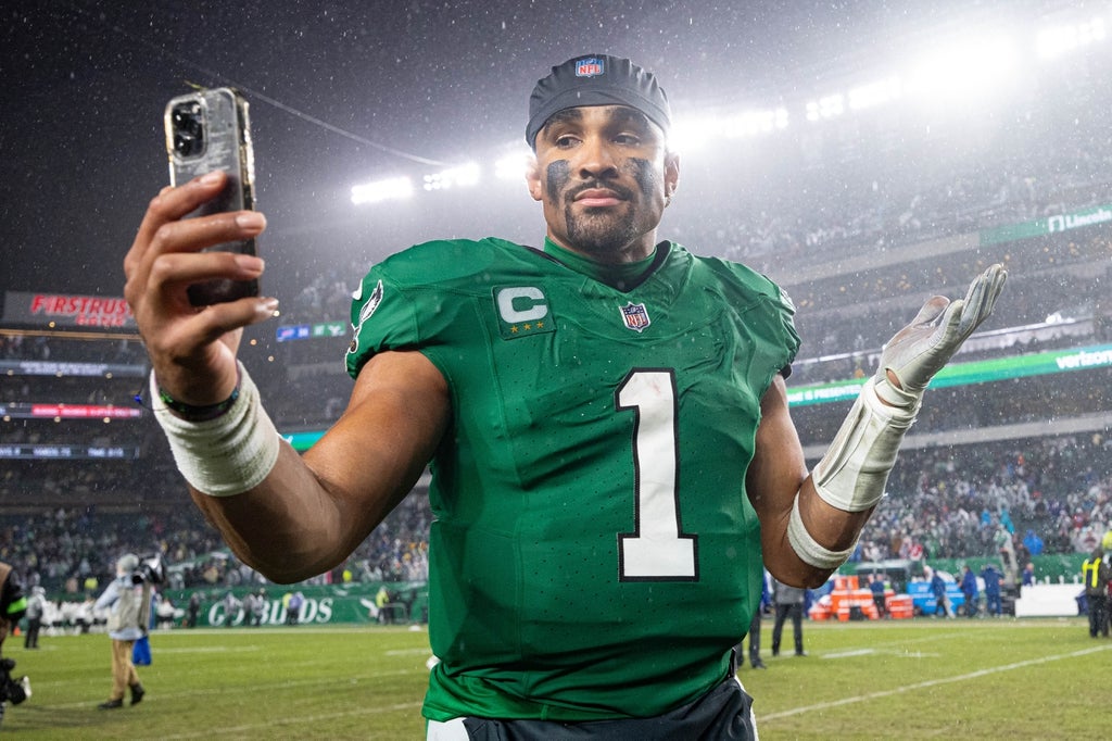 Philadelphia Eagles quarterback Jalen Hurts reacts with a smart phone while walking off the field after an overtime victory against the Buffalo Bills at Lincoln Financial Field.