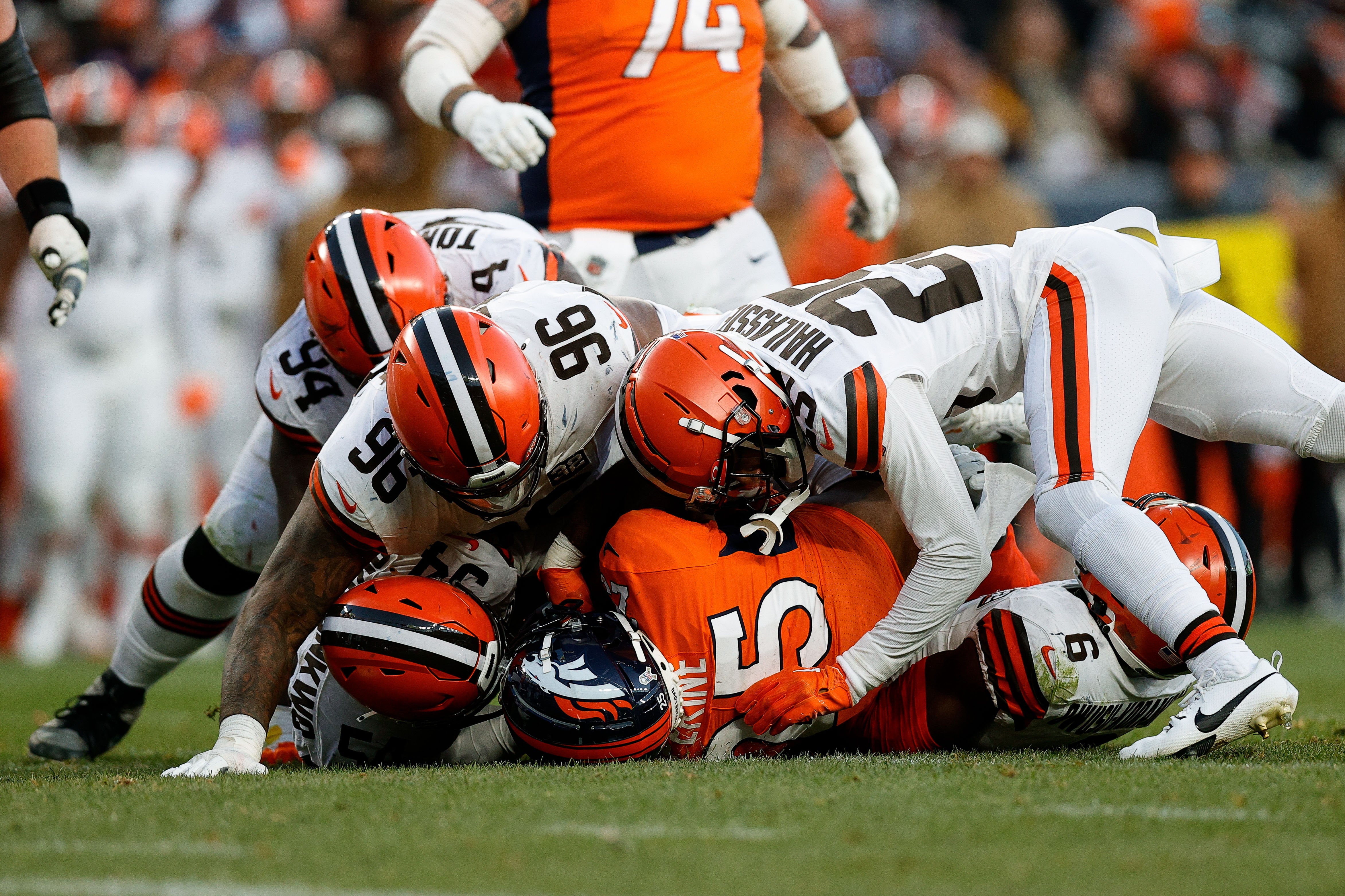 Nov 26, 2023; Denver, Colorado, USA; Denver Broncos running back Samaje Perine (25) is tackled by Cleveland Browns defensive end Ogbo Okoronkwo (54) and defensive tackle Dalvin Tomlinson (94) and defensive tackle Jordan Elliott (96) and cornerback Kahlef Hailassie (25) and linebacker Jeremiah Owusu-Koramoah (6) in the third quarter at Empower Field at Mile High. Mandatory Credit: Isaiah J. Downing-USA TODAY Sports