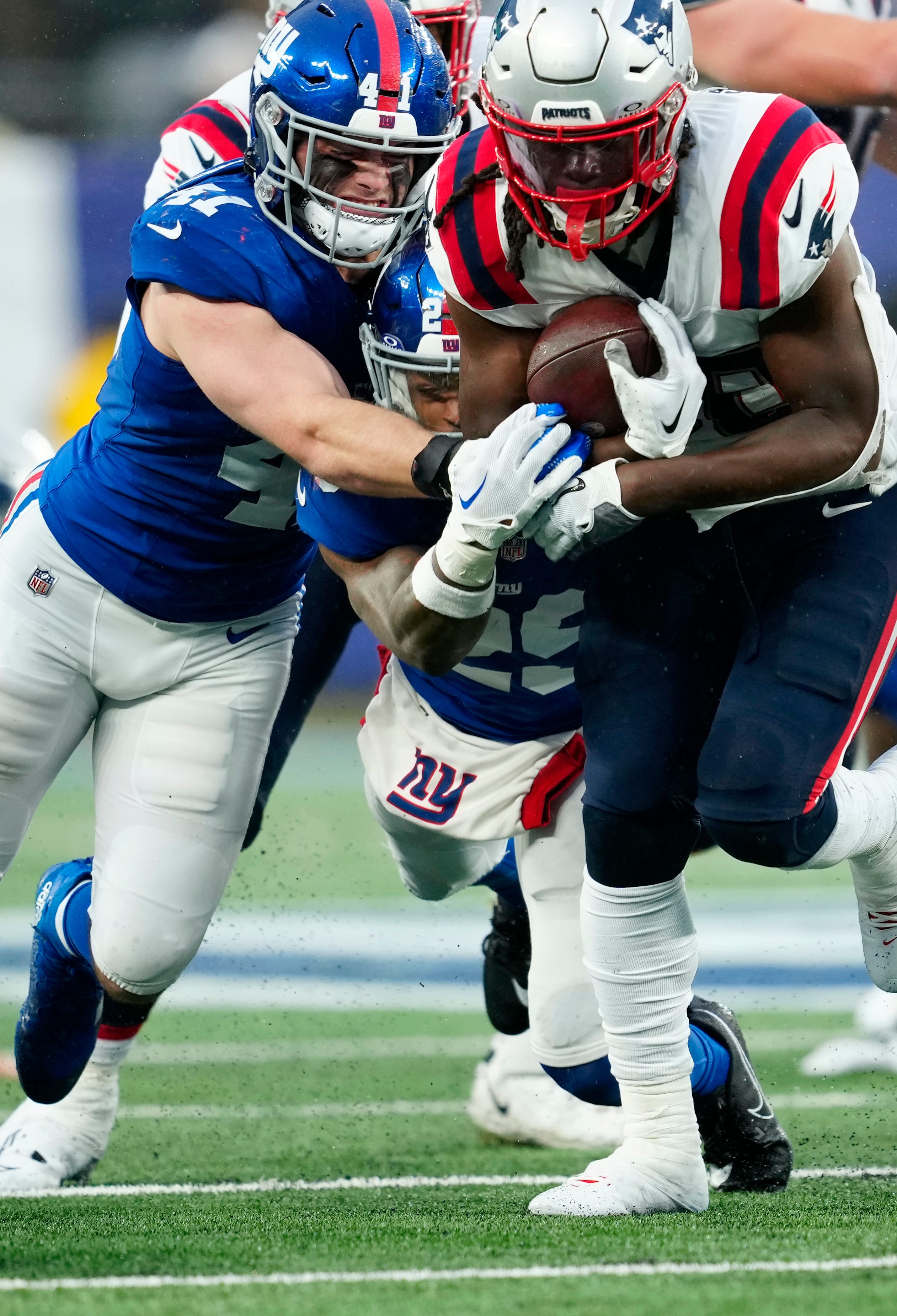 New England Patriots running back Rhamondre Stevenson (38) runs through New York Giants linebacker Micah McFadden (41) and New York Giants safety Xavier McKinney (29), during the fourth quarter, Sunday, November 26, 2023.
