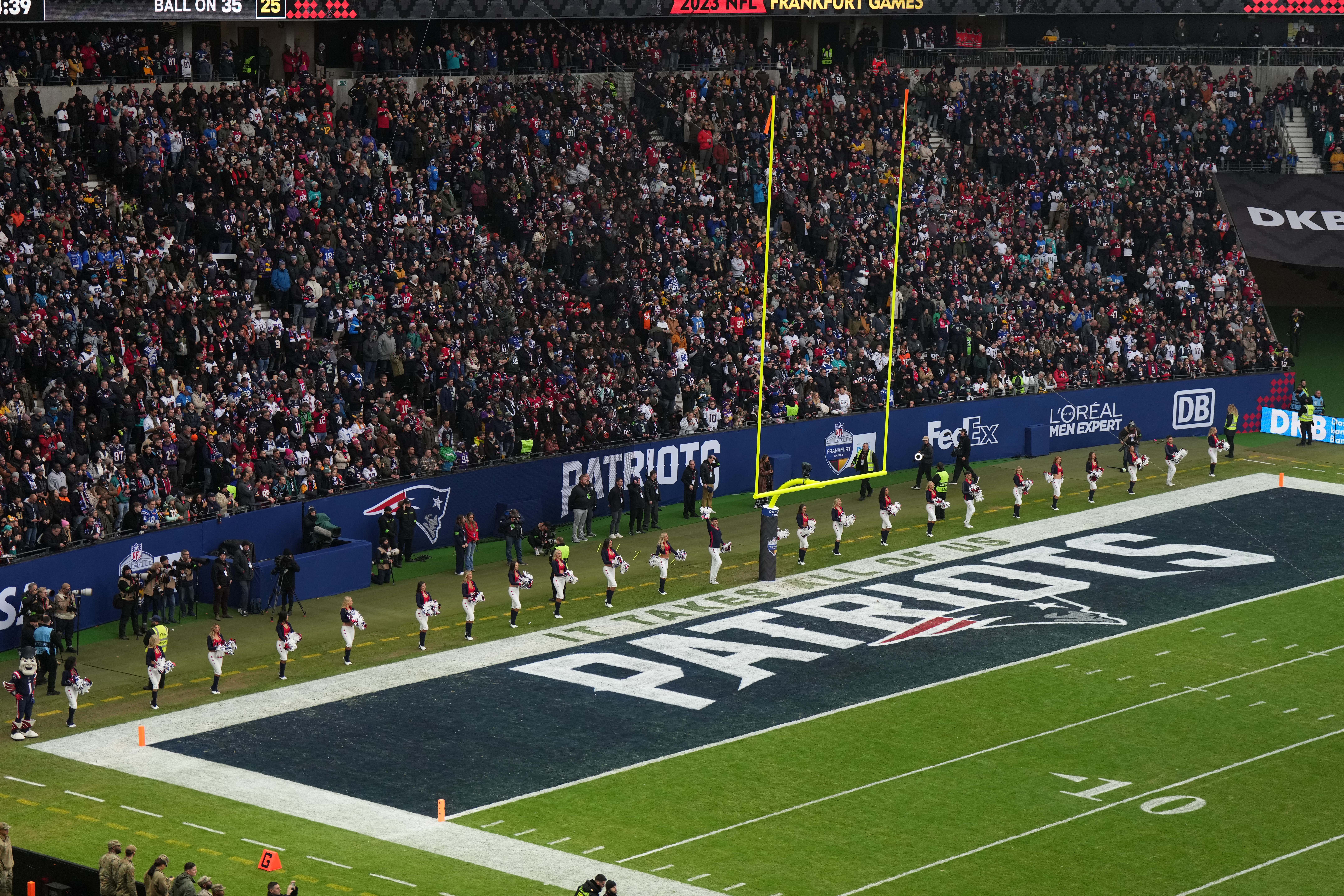 New England Patriots cheerleaders observe the playing of the national anthem in the end zone with a Patriots logo during an NFL International Series game against the Indianapolis Colts at Deutsche Bank Park