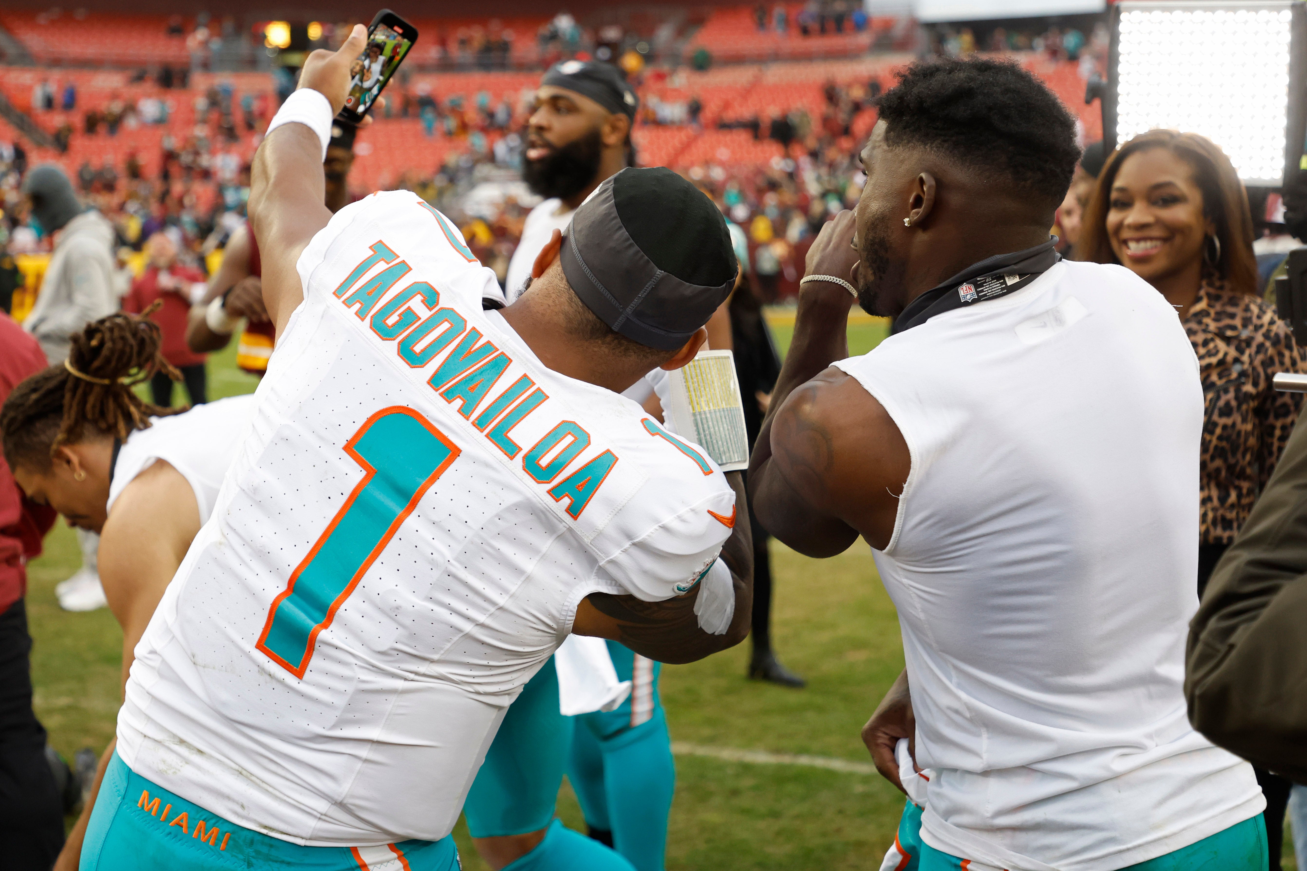 Miami Dolphins quarterback Tua Tagovailoa makes a video with Dolphins wide receiver Tyreek Hill (R) on the field after their game against the Washington Commanders at FedExField.