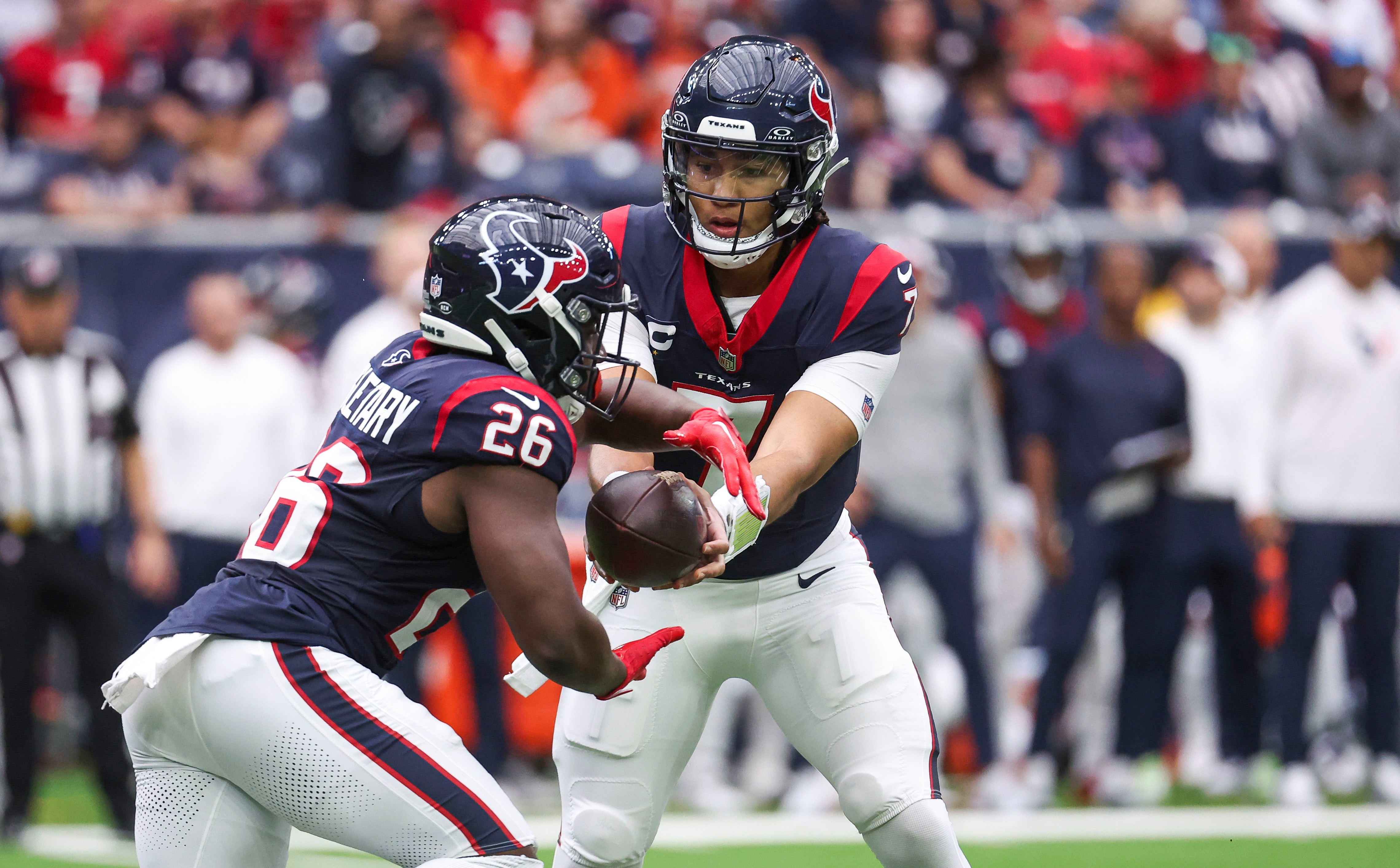 Dec 3, 2023; Houston, Texas, USA; Houston Texans quarterback C.J. Stroud (7) hands off to running back Devin Singletary (26) during the first quarter against the Denver Broncos at NRG Stadium. Mandatory Credit: Troy Taormina-USA TODAY Sports