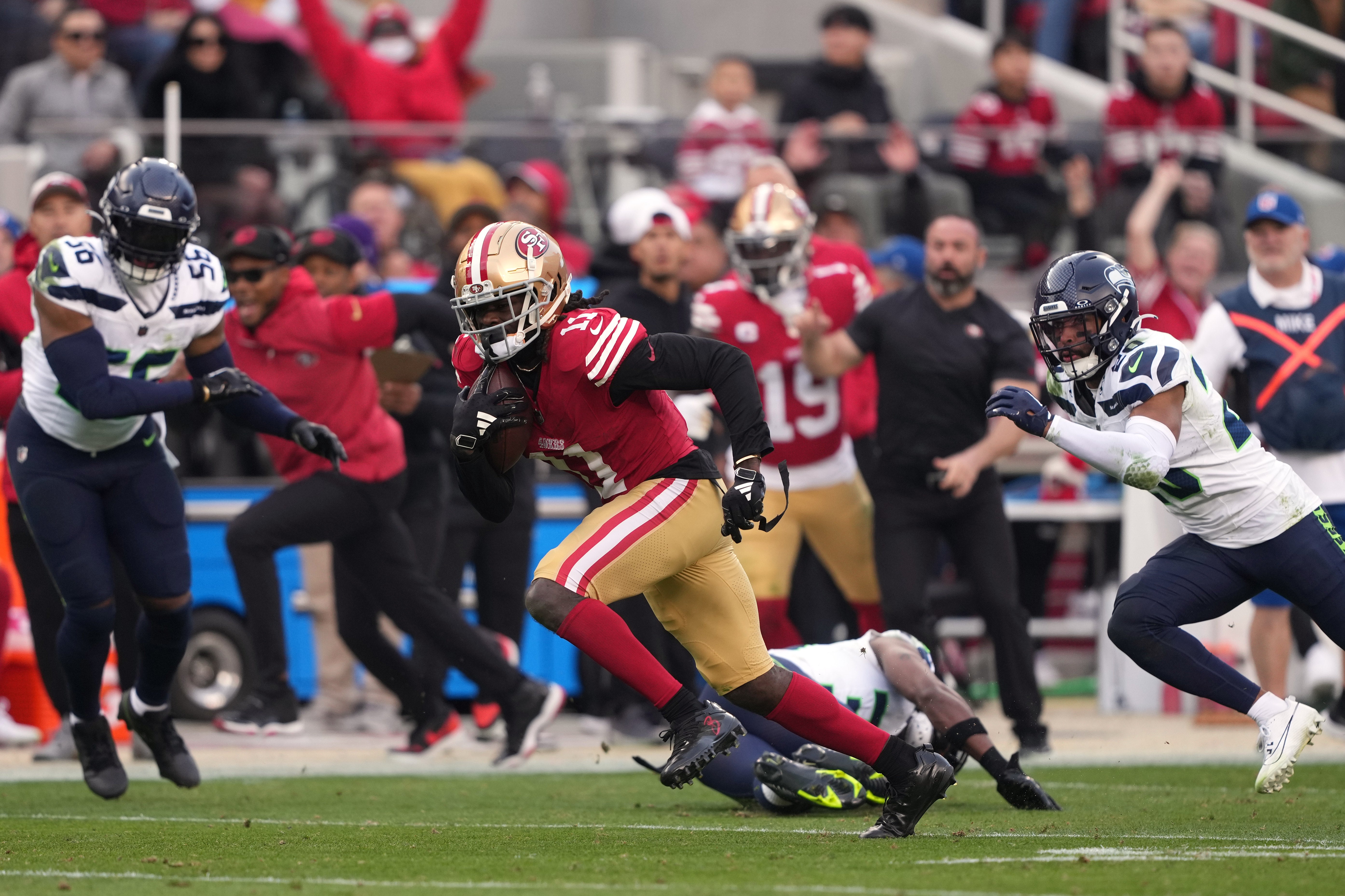 Dec 10, 2023; Santa Clara, California, USA; San Francisco 49ers wide receiver Brandon Aiyuk (11) runs after a catch against Seattle Seahawks linebacker Jordyn Brooks (56) and safety Julian Love (20) during the fourth quarter at Levi's Stadium.