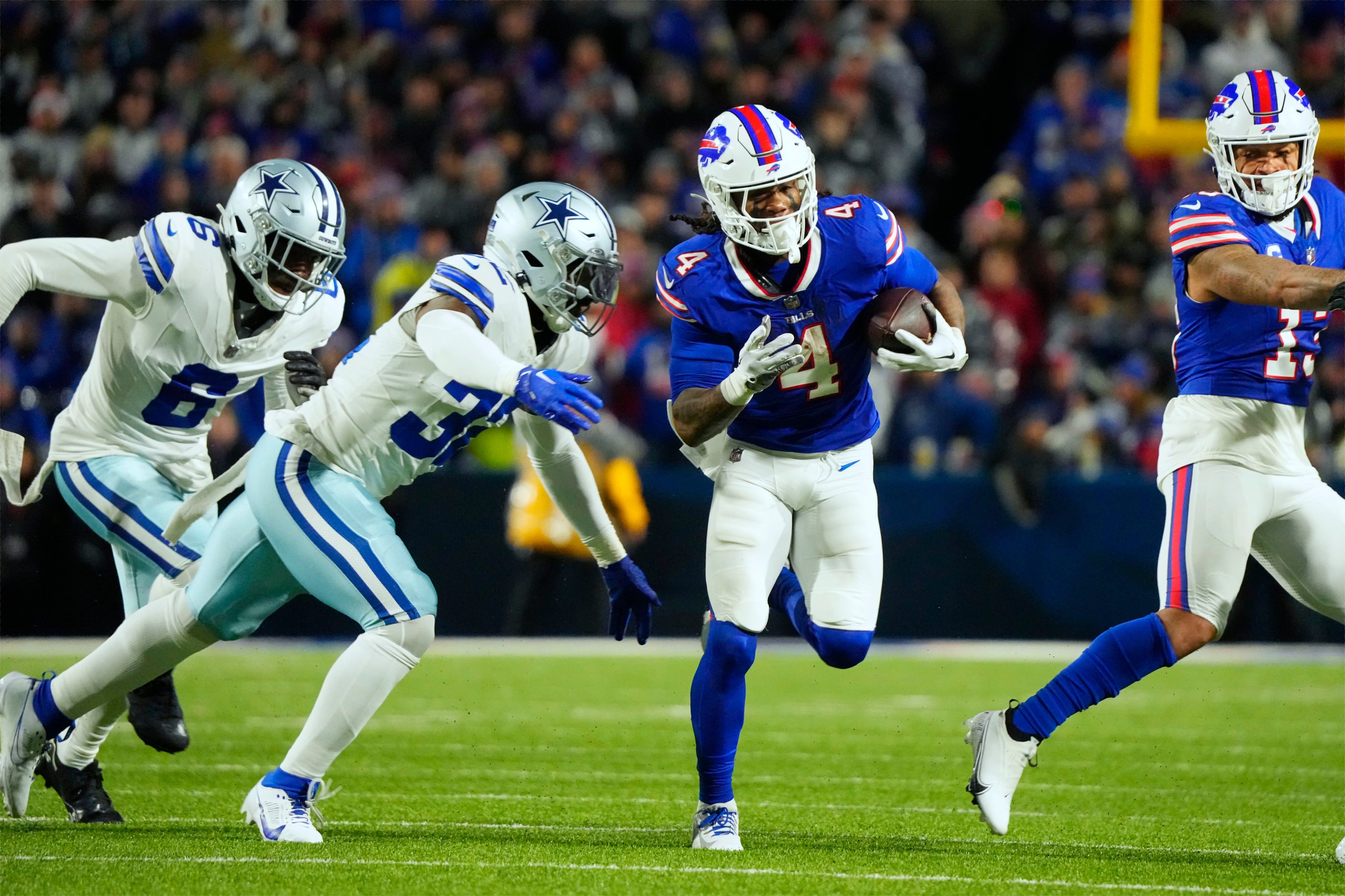 Buffalo Bills running back James Cook (4) runs the ball pressured by Dallas Cowboys linebacker Rashaan Evans (32) in the first half at Highmark Stadium.