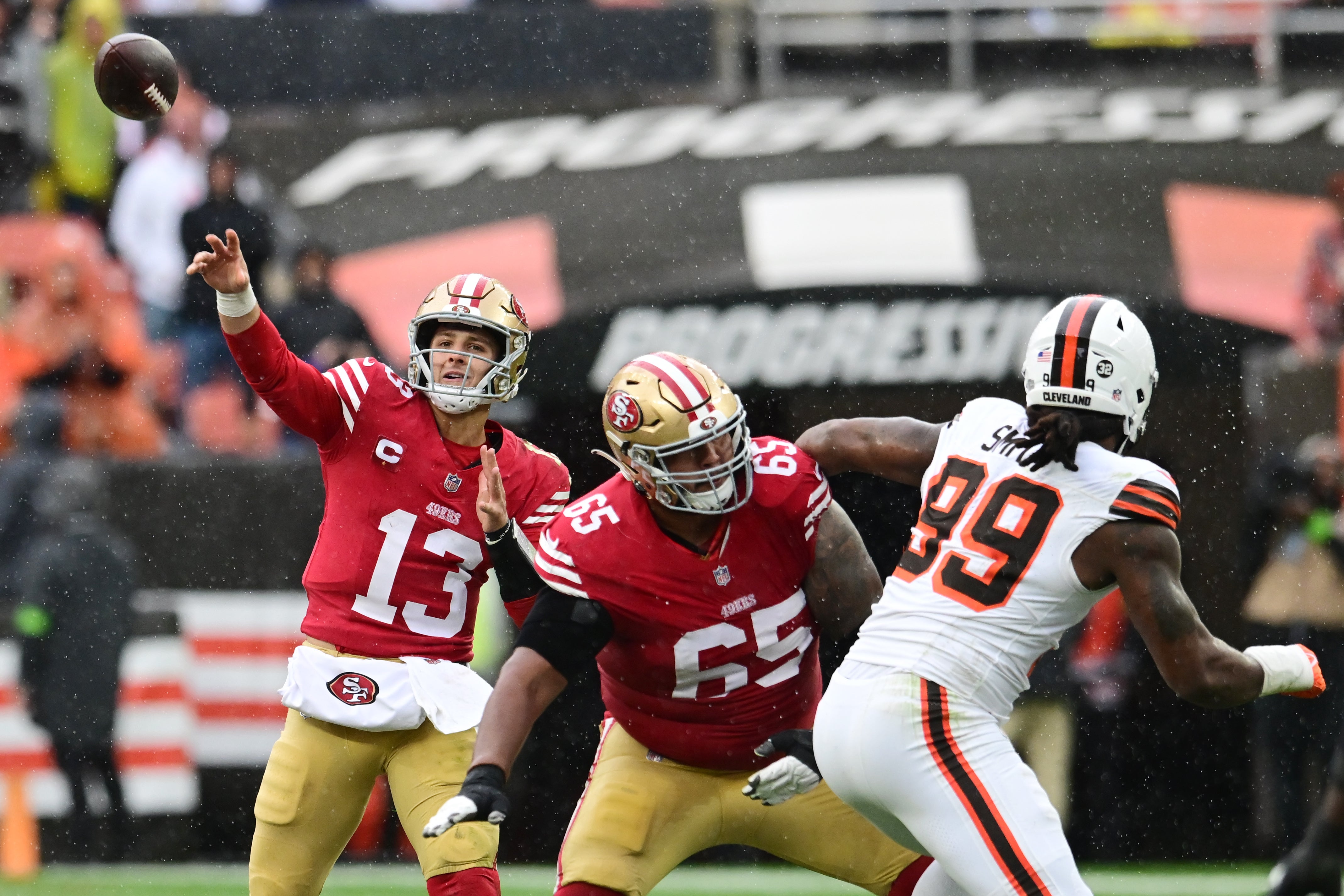Oct 15, 2023; Cleveland, Ohio, USA; San Francisco 49ers quarterback Brock Purdy (13) throws a pass as guard Aaron Banks (65) blocks Cleveland Browns defensive end Za'Darius Smith (99) during the first half at Cleveland Browns Stadium.