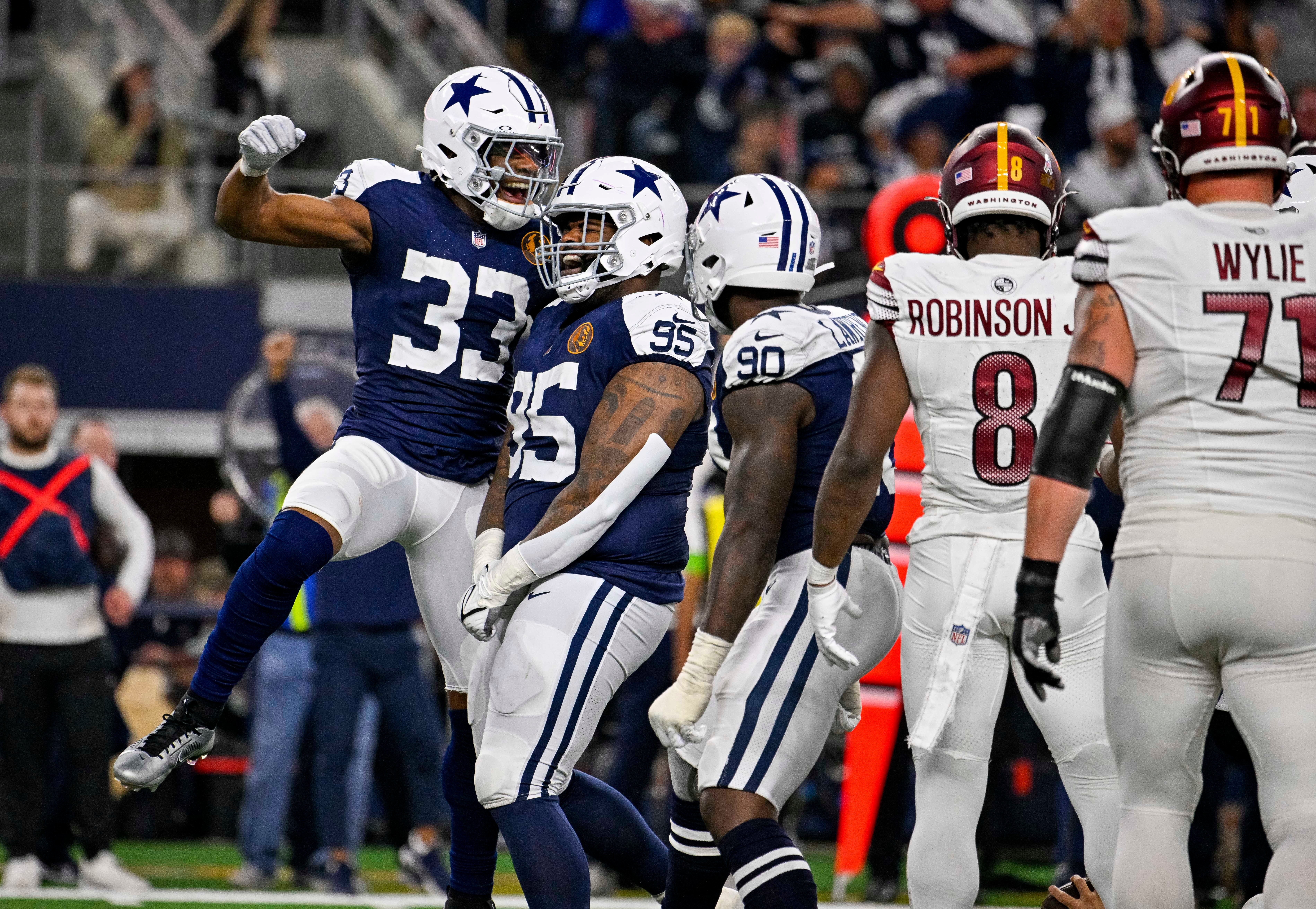 Dallas Cowboys linebacker Damone Clark (33) and defensive tackle Johnathan Hankins (95) and defensive end DeMarcus Lawrence (90) celebrates after the Cowboys make a stop on the Washington Commanders on fourth down to turn the ball over on downs during the second half at AT&T Stadium.