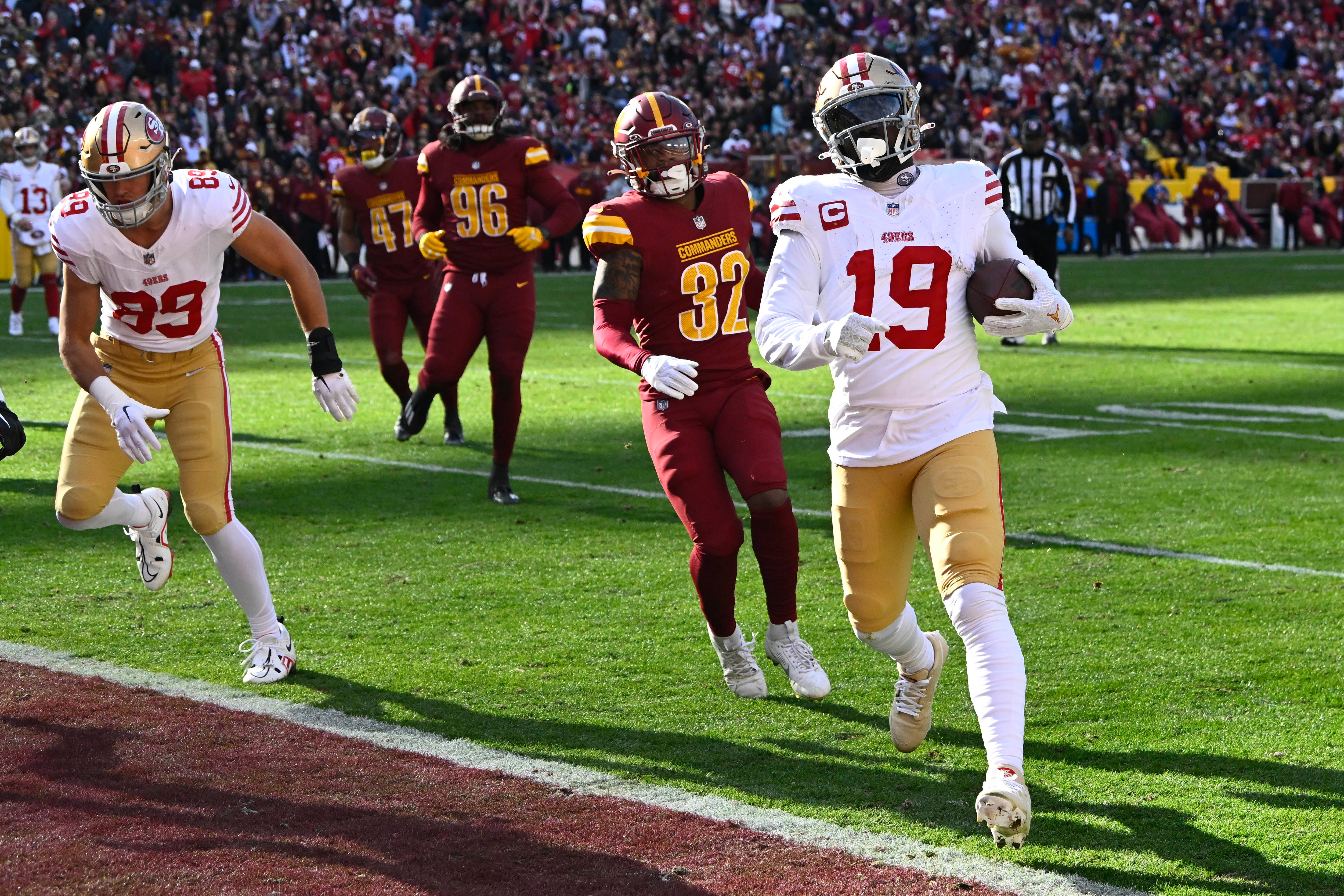 Dec 31, 2023; Landover, Maryland, USA; San Francisco 49ers wide receiver Deebo Samuel (19) scores a touchdown as Washington Commanders safety Terrell Burgess (32) looks on during the first half at FedExField.