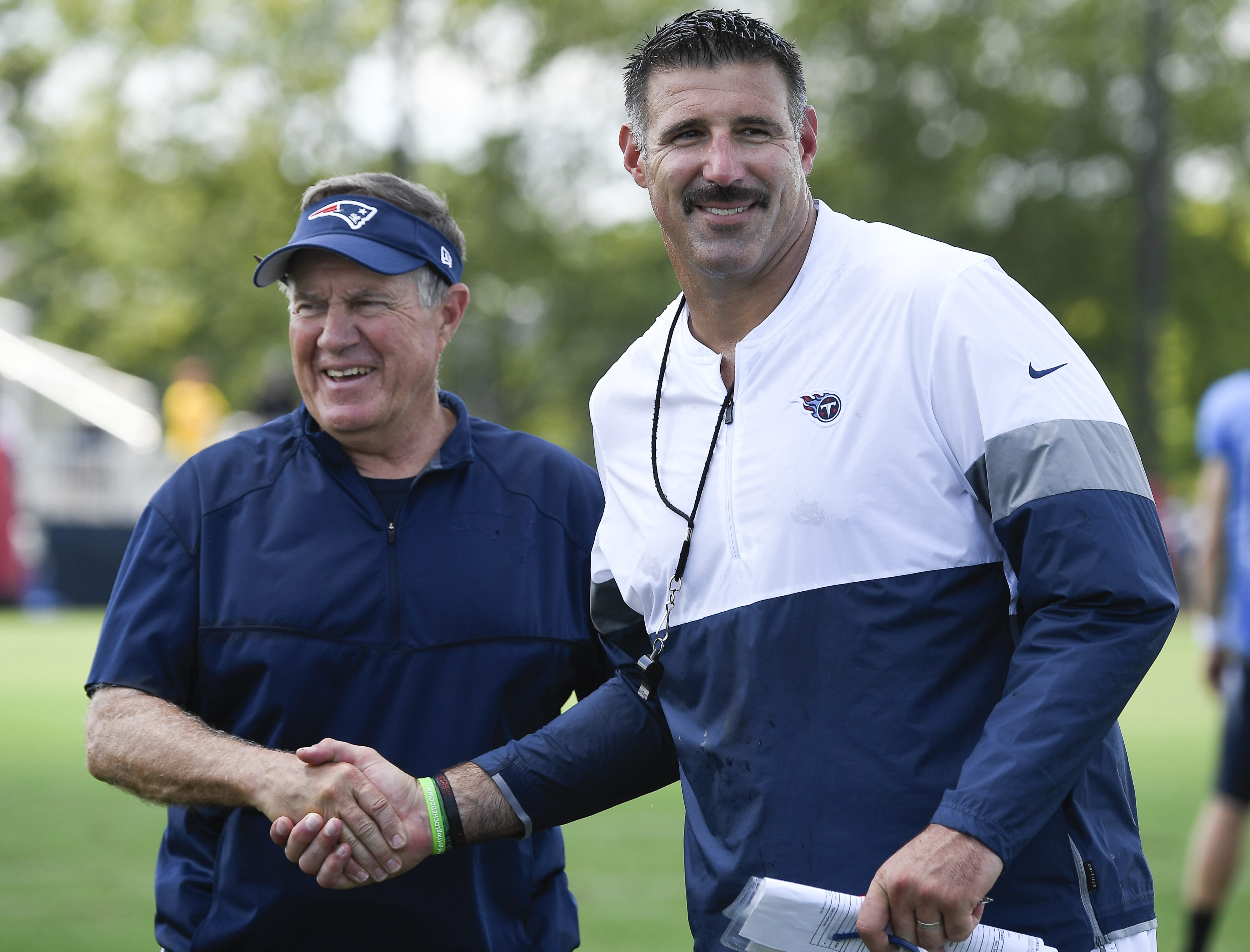 New England Patriots head coach Bill Belichick, left, shares a laugh with Tennessee Titans head coach Mike Vrabel after a joint training camp practice at Saint Thomas Sports Park Aug.