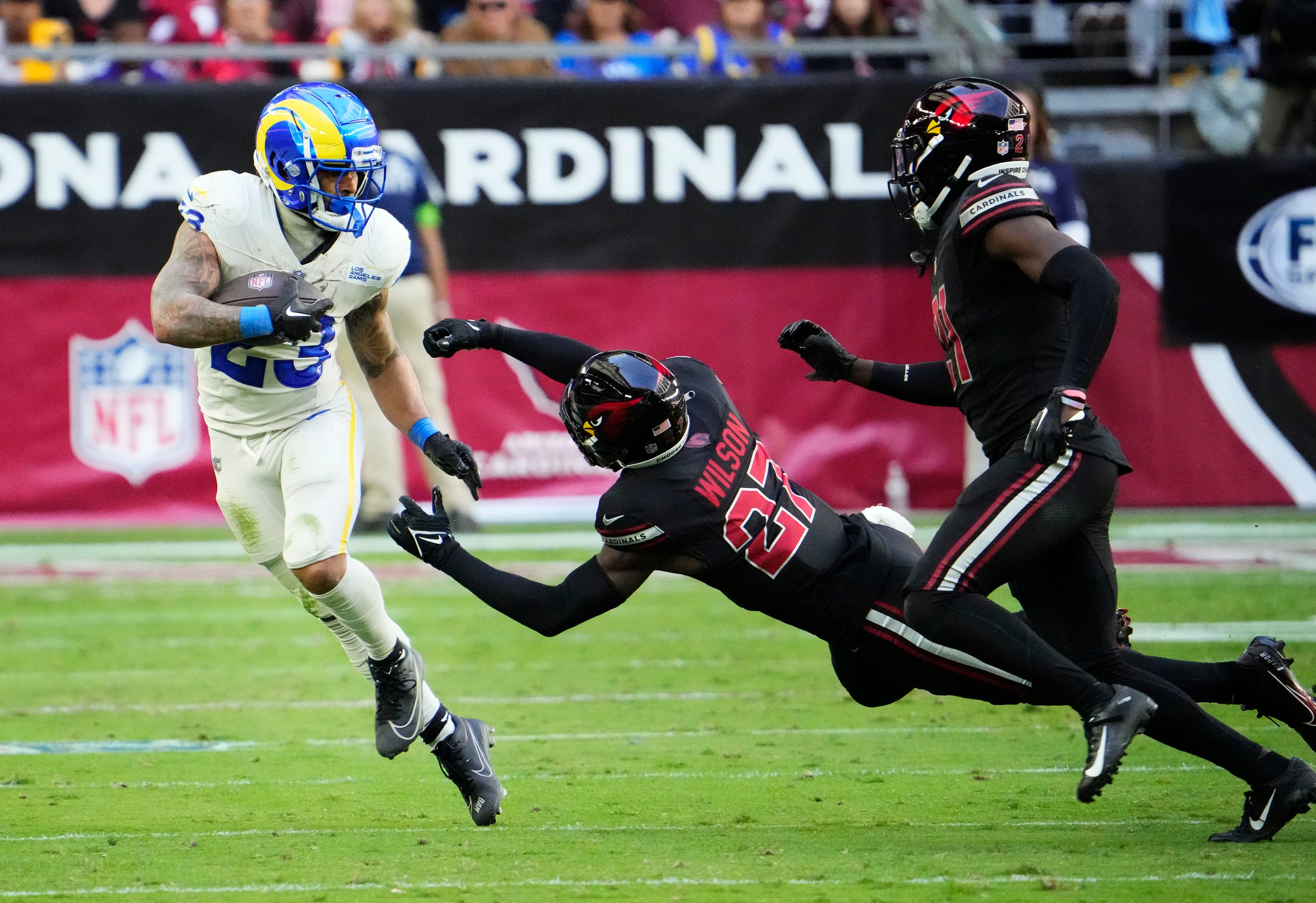 Nov 26, 2023; Glendale, AZ, USA; Los Angeles Rams running back Kyren Williams (23) pushes aside Arizona Cardinals cornerback Divaad Wilson (27) in the first half at State Farm Stadium. Mandatory Credit: Rob Schumacher-Arizona Republic