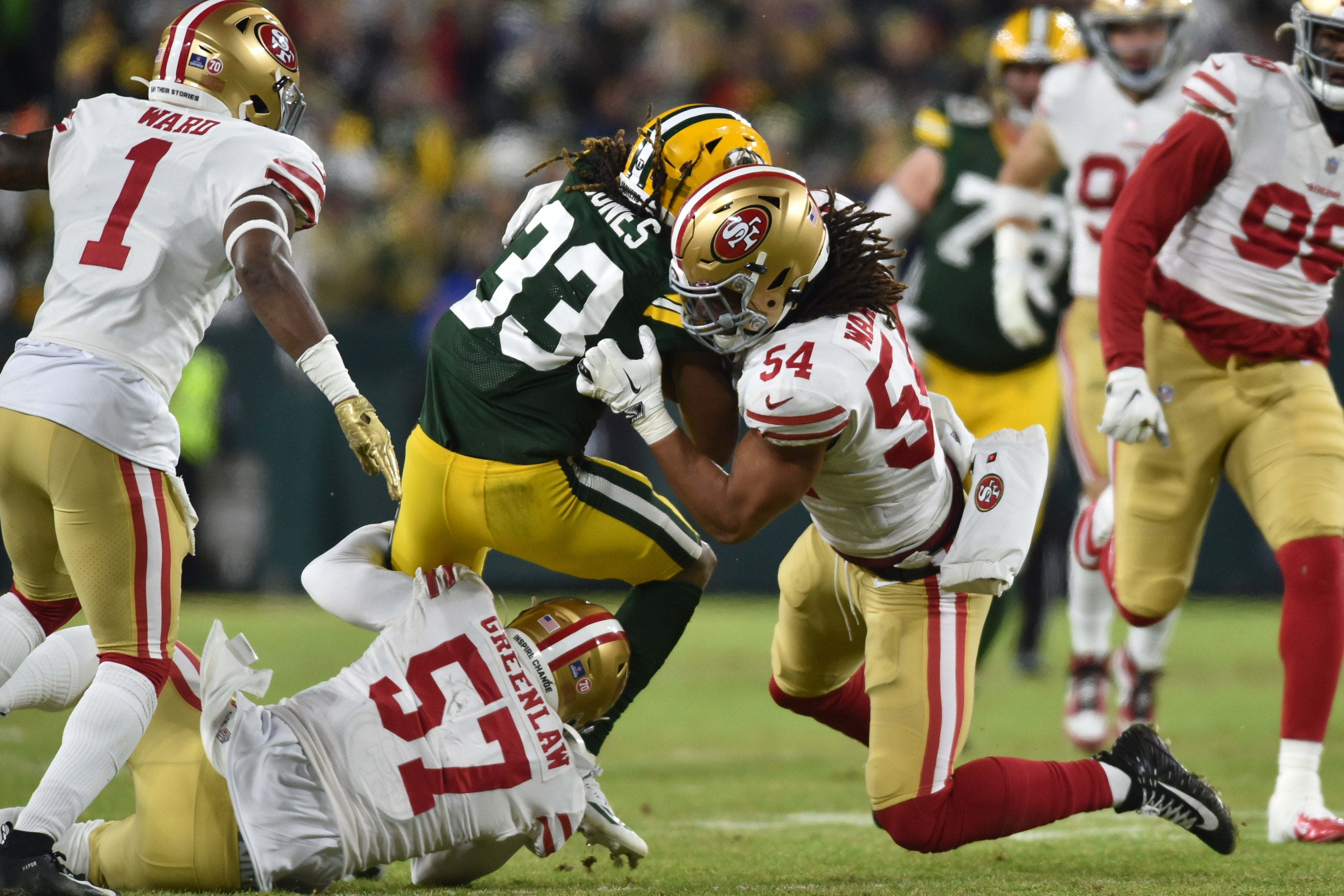 Jan 22, 2022; Green Bay, Wisconsin, USA; Green Bay Packers running back Aaron Jones (33) and San Francisco 49ers middle linebacker Fred Warner (54) and outside linebacker Dre Greenlaw (57) in action during a NFC Divisional playoff football game at Lambeau Field.