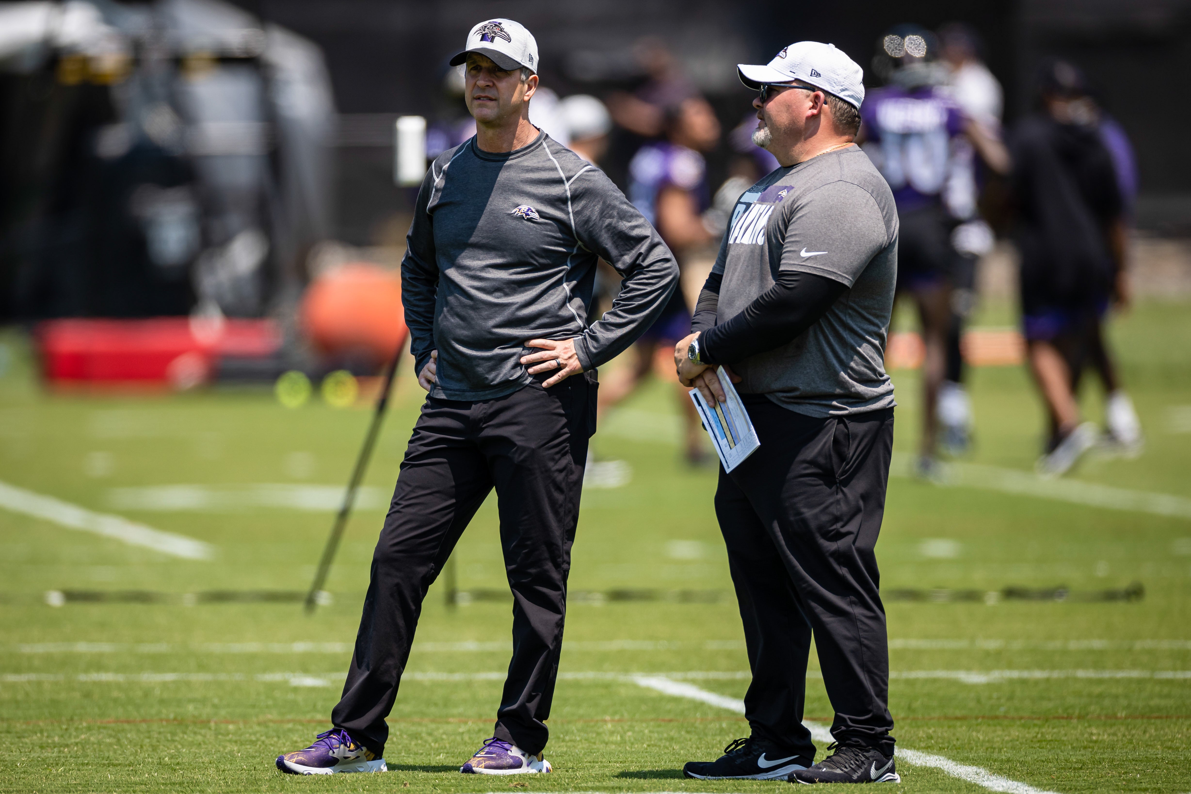 May 26, 2021; Owings Mills, Maryland, USA; Baltimore Ravens head coach John Harbaugh and offensive coordinator Greg Roman look on during an OTA at Under Armour Performance Center.