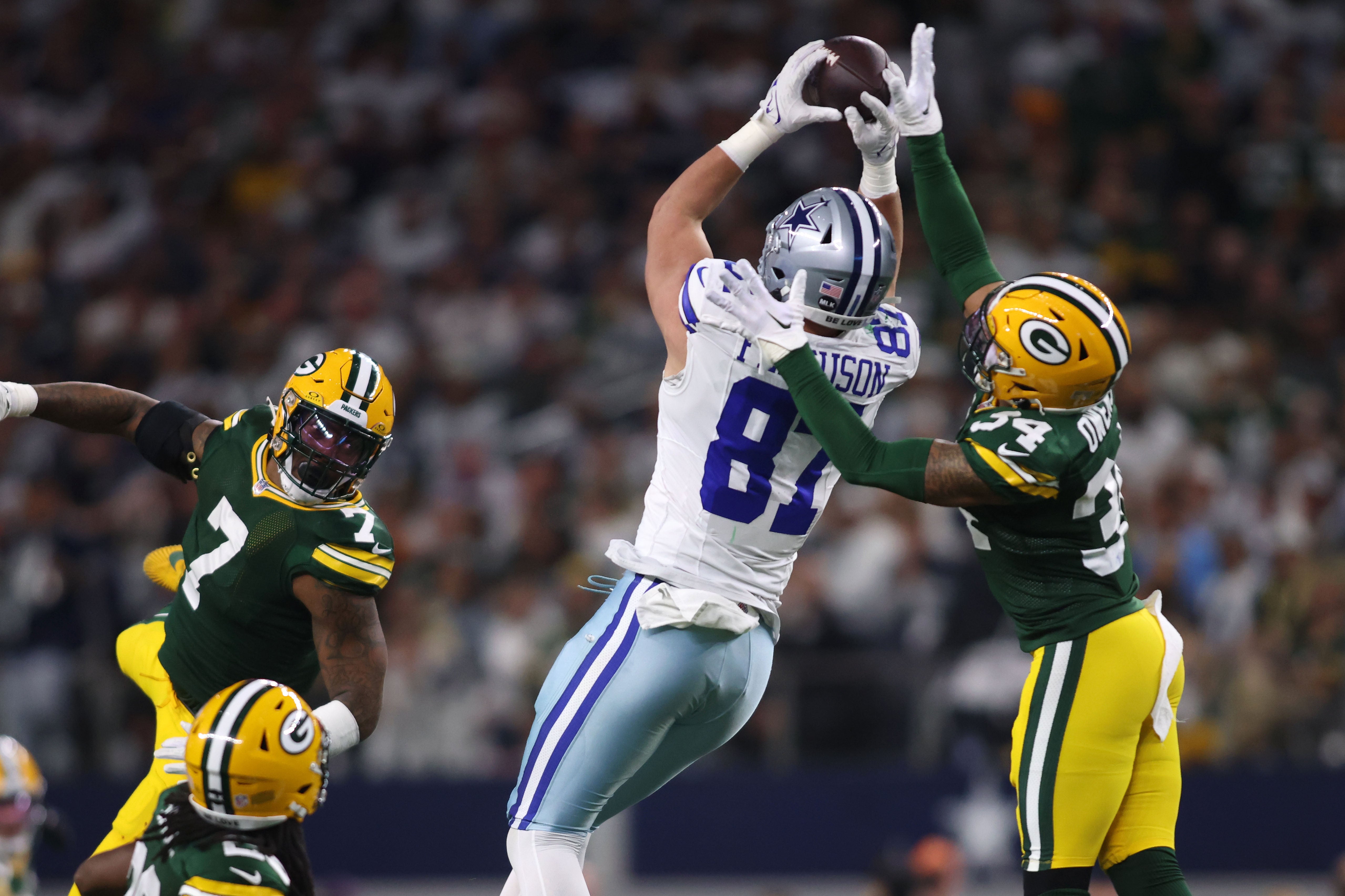 Dallas Cowboys tight end Jake Ferguson (87) makes a catch over Green Bay Packers linebacker Quay Walker (7) and safety Jonathan Owens (34) during the first half for the 2024 NFC wild card game at AT&T Stadium.