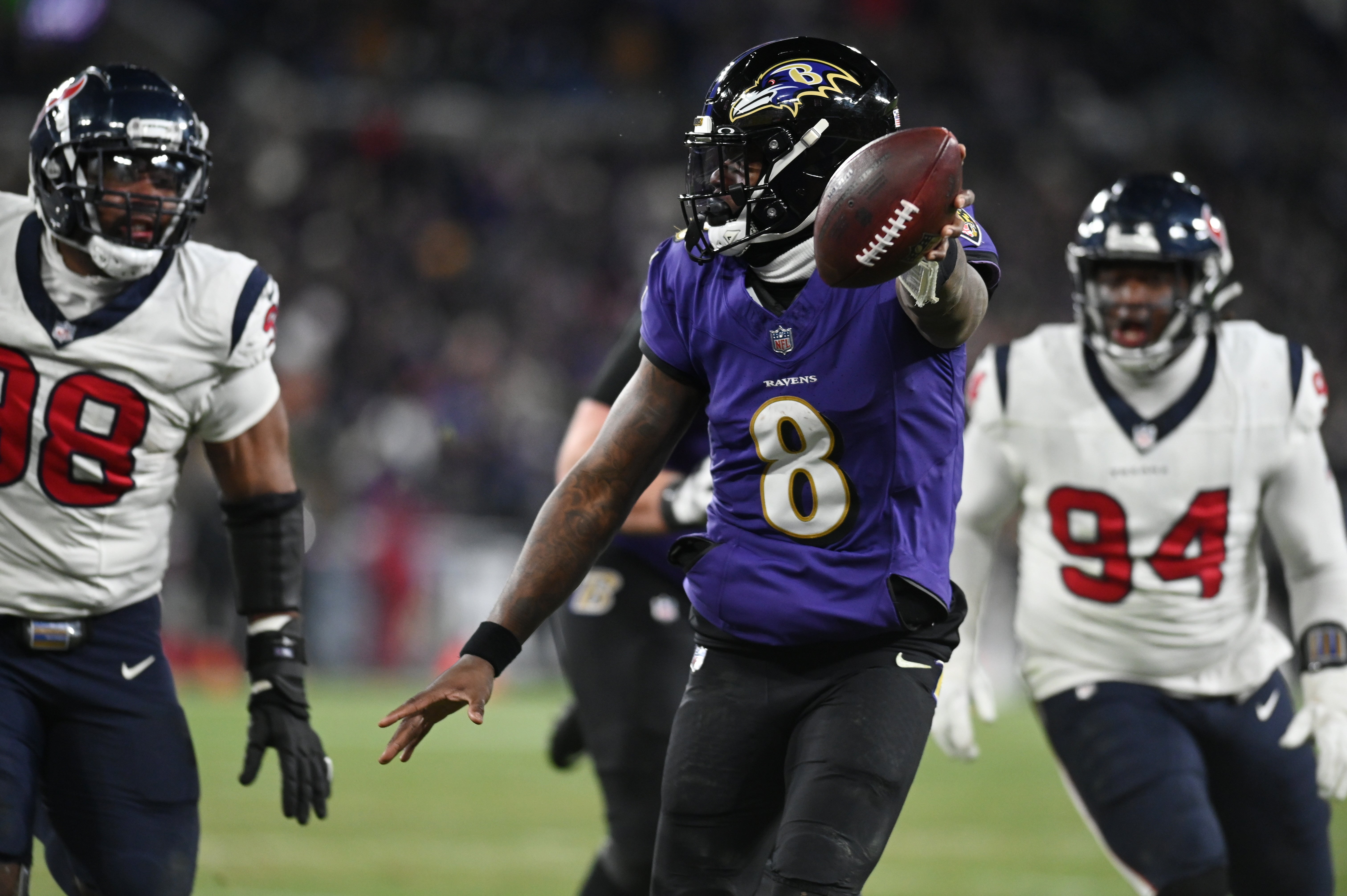 Jan 20, 2024; Baltimore, MD, USA; Baltimore Ravens quarterback Lamar Jackson (8) runs the ball to score a touchdown against Houston Texans defensive tackle Sheldon Rankins (98) and defensive tackle Khalil Davis (94) during the fourth quarter of a 2024 AFC divisional round game at M&T Bank Stadium.