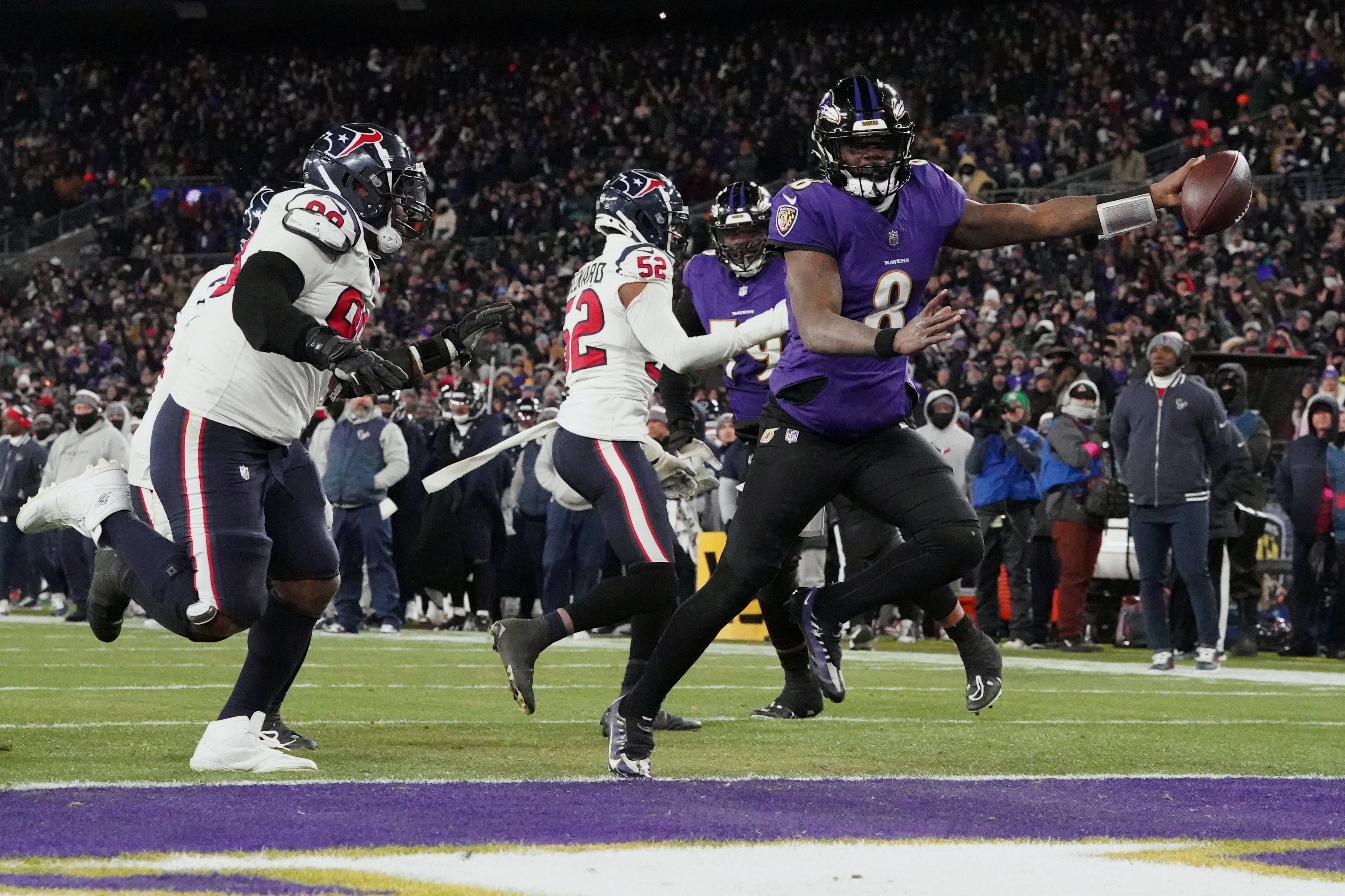 Baltimore Ravens quarterback Lamar Jackson (8) runs the ball to score a touchdown against Houston Texans defensive tackle Sheldon Rankins (98) and defensive end Jonathan Greenard (52) during the fourth quarter of a 2024 AFC divisional round game at M&T Bank Stadium.