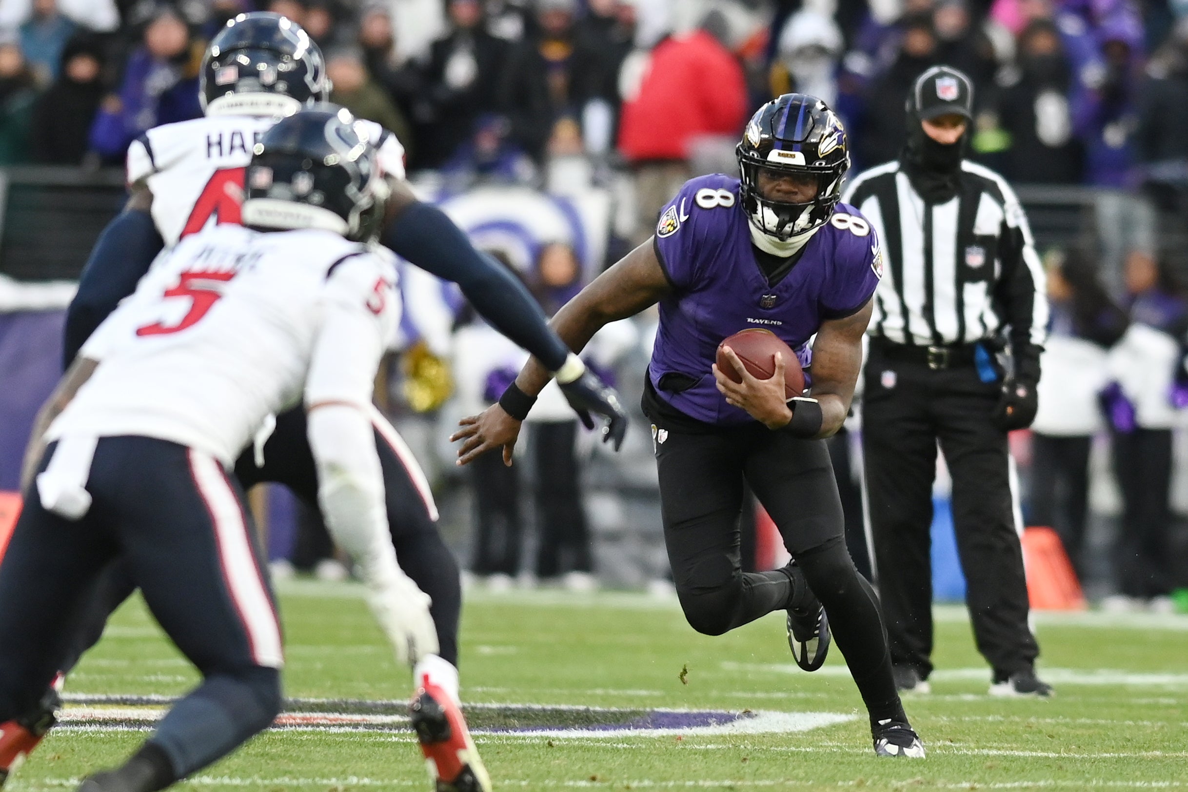 Baltimore Ravens quarterback Lamar Jackson (8) runs the ball against Houston Texans safety Jalen Pitre (5) and linebacker Christian Harris (48) during the first quarter of a 2024 AFC divisional round game at M&T Bank Stadium.