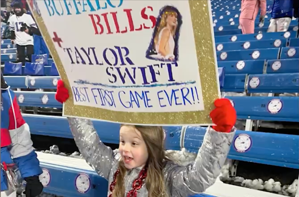 8-year-old Ella Piazza holds up a sign at the Buffalo Bills game in support for the home team along with pop star Taylor Swift