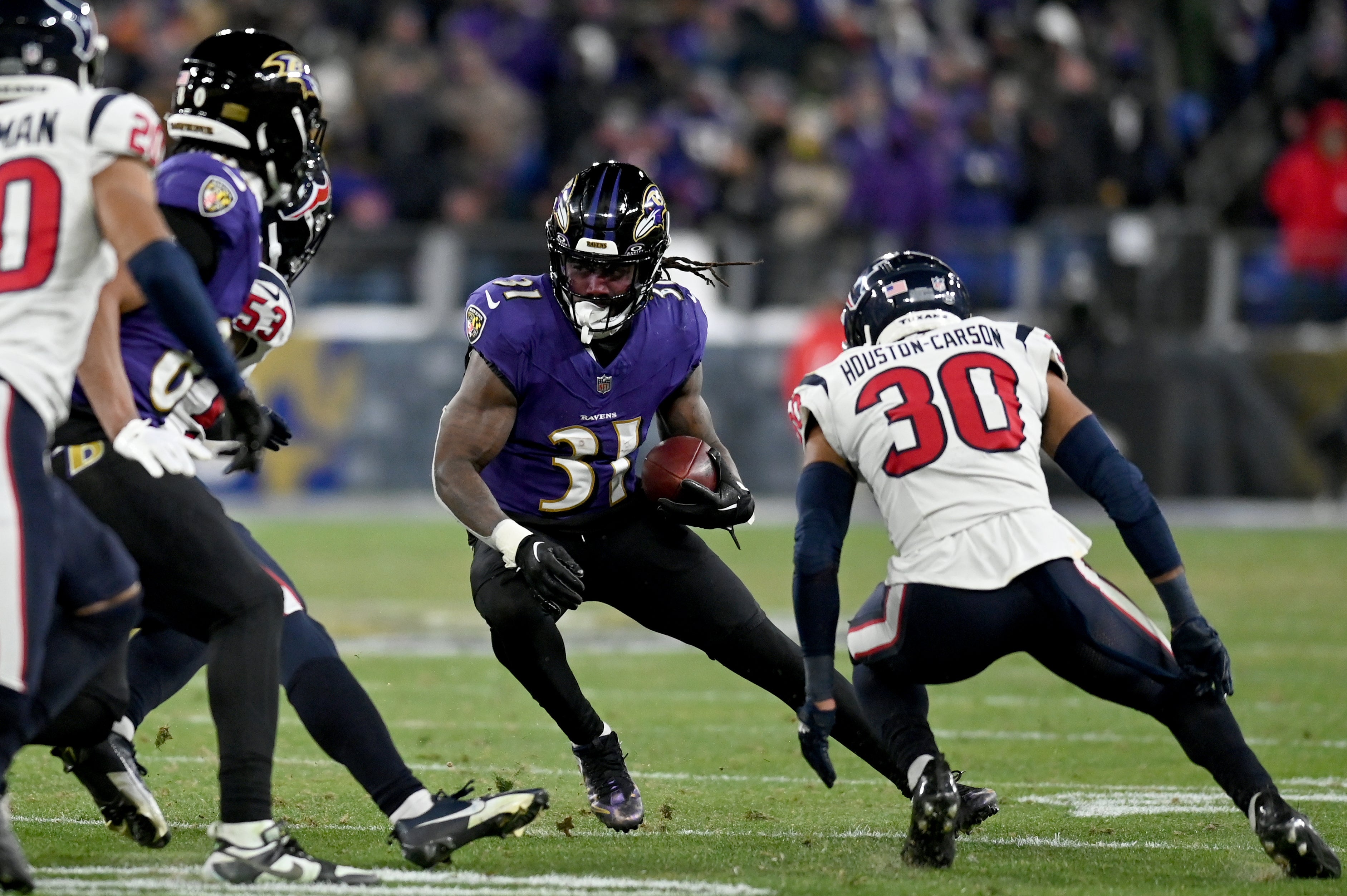 Baltimore Ravens running back Dalvin Cook (31) runs the ball against Houston Texans linebacker Blake Cashman (53) and safety DeAndre Houston-Carson (30) during the fourth quarter of a 2024 AFC divisional round game at M&T Bank Stadium.