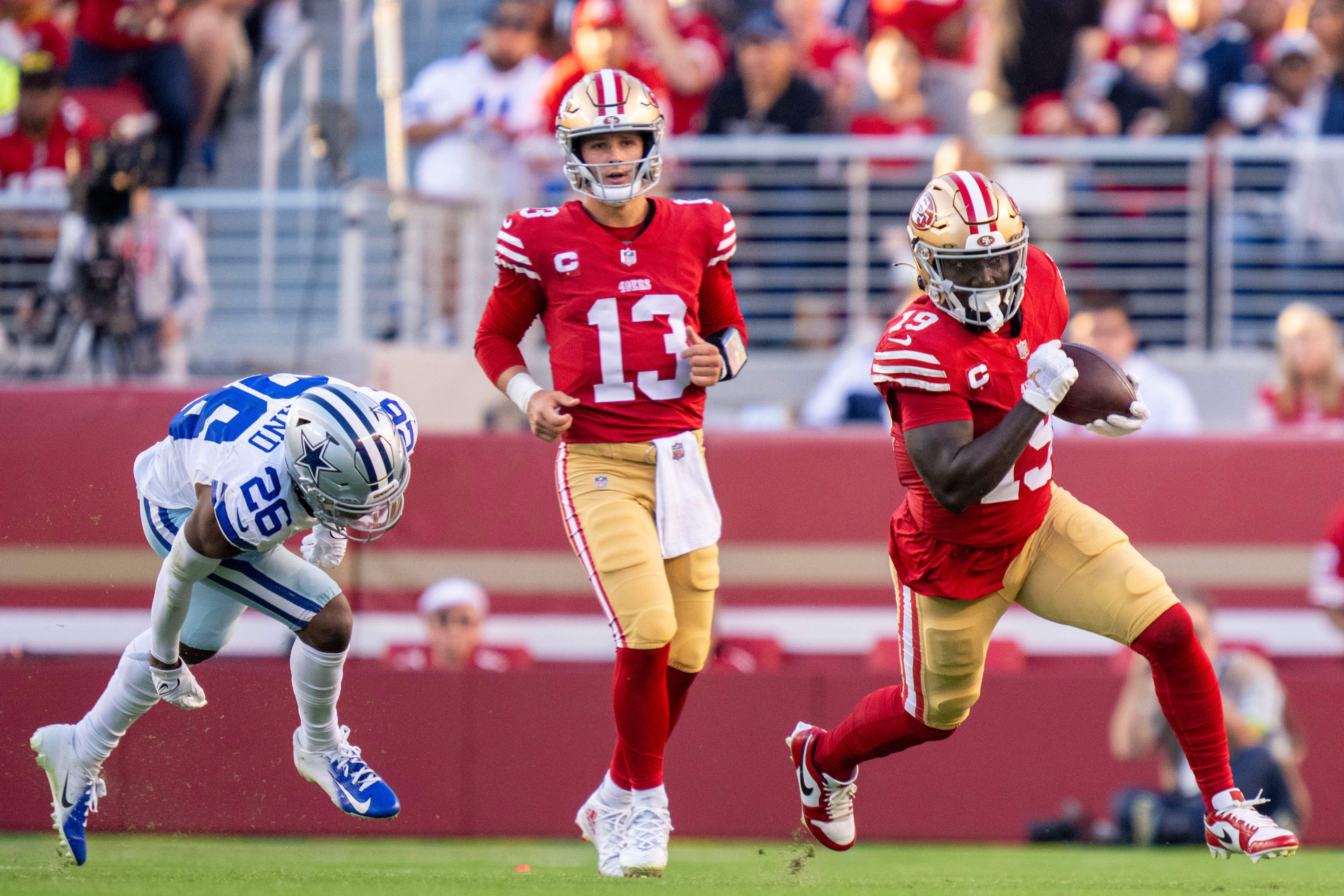 October 8, 2023; Santa Clara, California, USA; San Francisco 49ers wide receiver Deebo Samuel (19) runs the football against Dallas Cowboys cornerback DaRon Bland (26) in front of 49ers quarterback Brock Purdy (13) during the first quarter at Levi's Stadium.