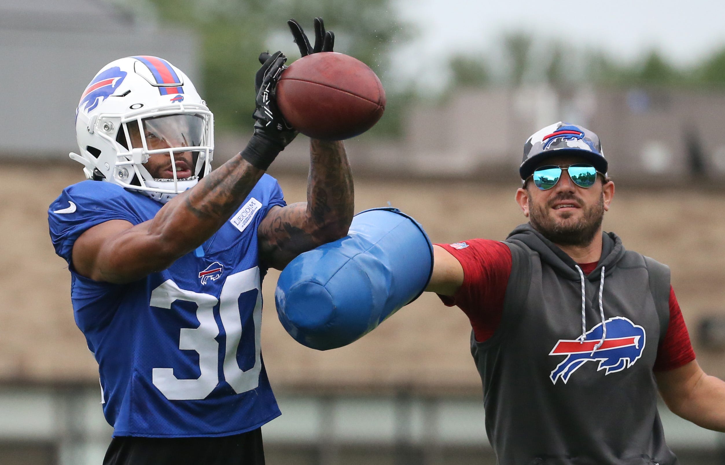 Bills cornerback Dane Jackson eyes in the ball as he is hit by linebackers coach Bobby Babich during interception drills on day nine of Buffalo Bills training camp at St. John Fisher University in Rochester