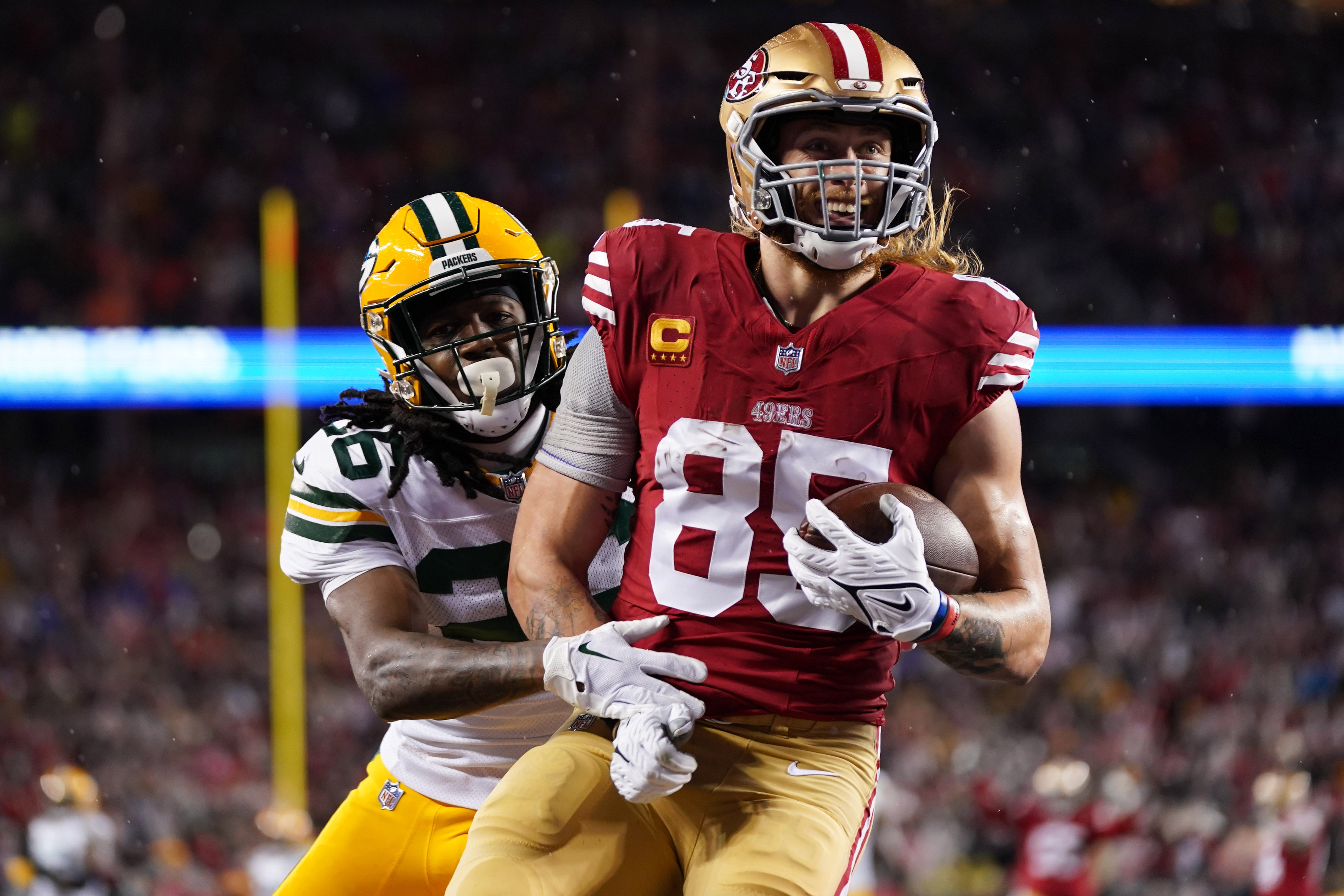 January 20, 2024; Santa Clara, CA, USA; San Francisco 49ers tight end George Kittle (85) scores a touchdown against Green Bay Packers safety Darnell Savage (26) during the second quarter in a 2024 NFC divisional round game at Levi's Stadium.