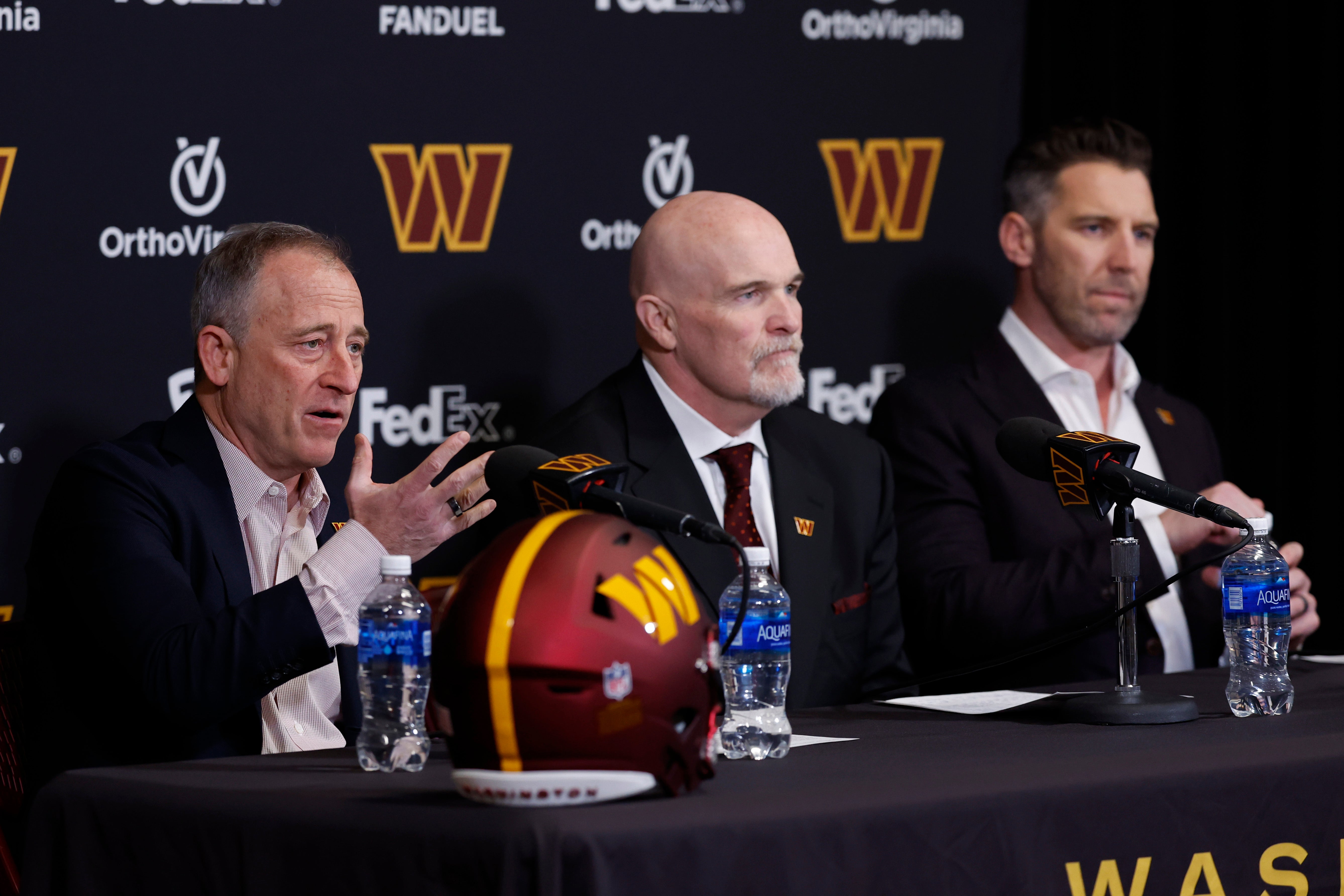 Feb 5, 2024; Ashburn, VA, USA; Washington Commanders majority owner Josh Harris (L) speaks as new Commanders head coach Dan Quinn (M) and Commanders general manager Adam Peters (R) listen during Quinn's introductory press conference at Commanders Park.