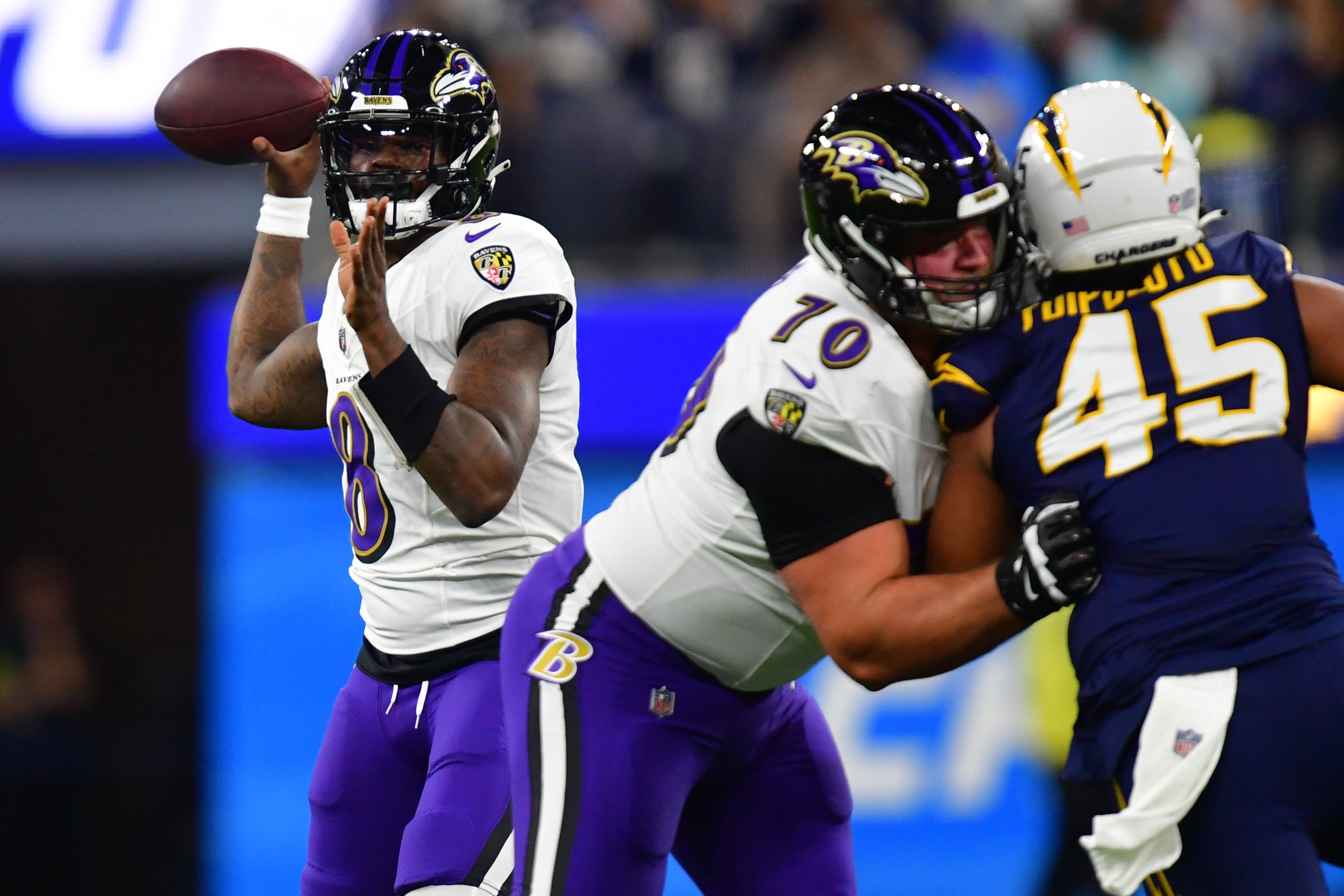 Nov 26, 2023; Inglewood, California, USA; Baltimore Ravens quarterback Lamar Jackson (8) throws as guard Kevin Zeitler (70) provides coverage against Los Angeles Chargers linebacker Tuli Tuipulotu (45) during the first half at SoFi Stadium.