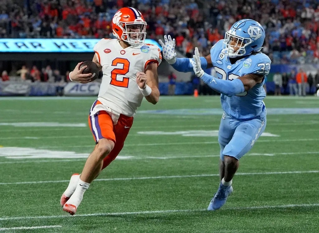 Clemson Tigers quarterback Cade Klubnik (2) runs against North Carolina Tar Heels linebacker Cedric Gray (33) during the first quarter of the ACC Championship game at Bank of America Stadium.
