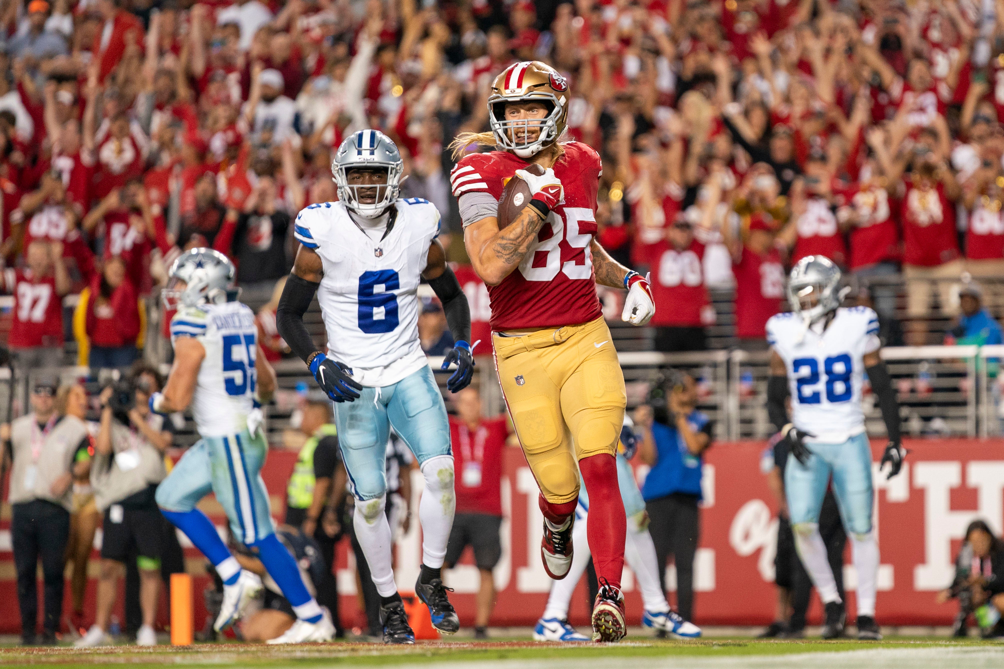 October 8, 2023; Santa Clara, California, USA; San Francisco 49ers tight end George Kittle (85) scores a touchdown against Dallas Cowboys safety Donovan Wilson (6) during the third quarter at Levi's Stadium.