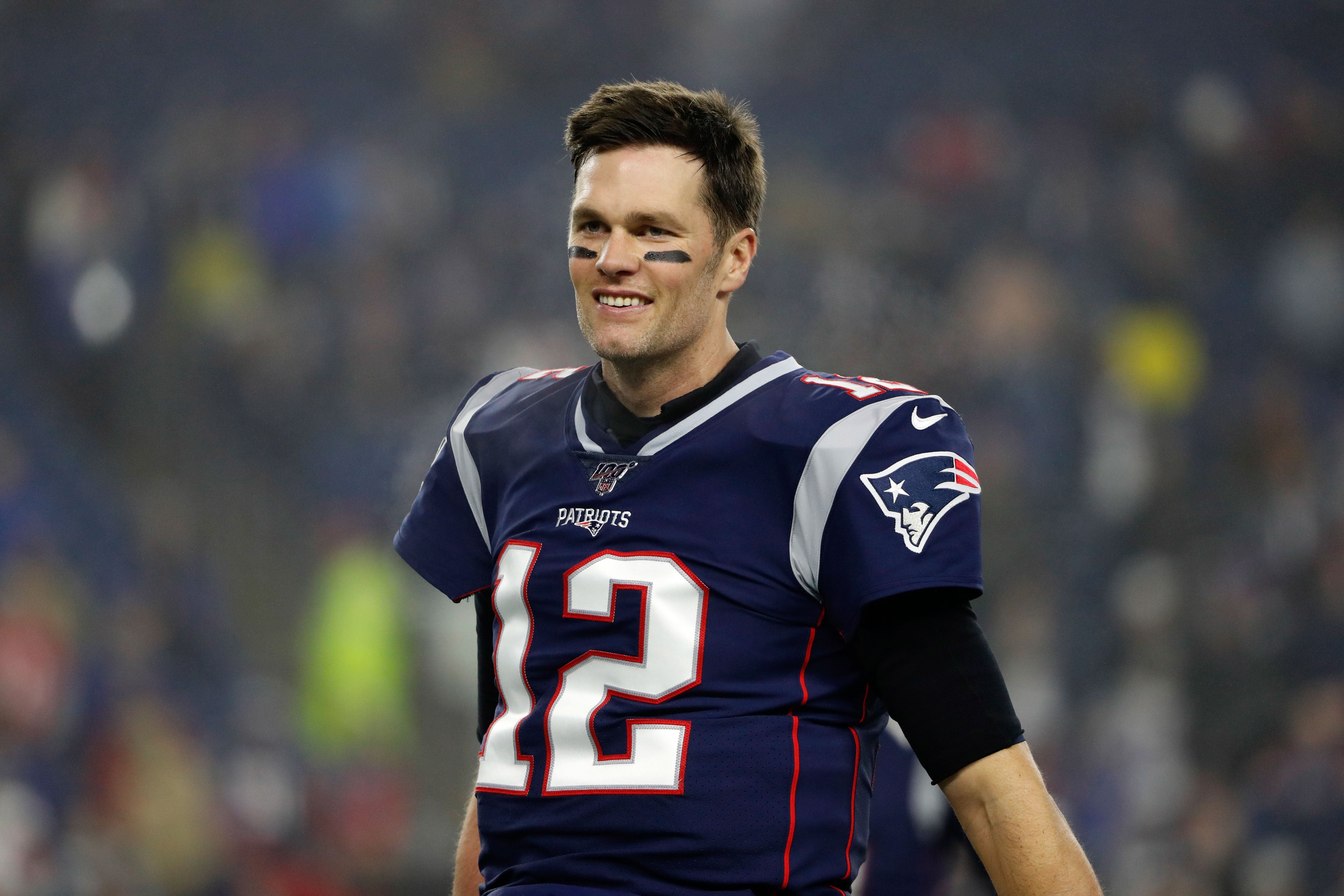 Jan 4, 2020; Foxborough, Massachusetts, USA; New England Patriots quarterback Tom Brady (12) smiles at teammates before their playoff game against the Tennessee Titans at Gillette Stadium.