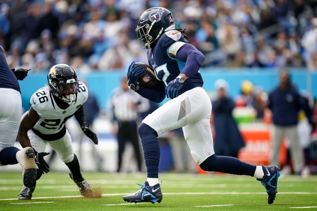 Tennessee Titans running back Derrick Henry (22) runs the ball towards Jacksonville Jaguars safety Antonio Johnson (26) during the first quarter at Nissan Stadium in Nashville, Tennessee.