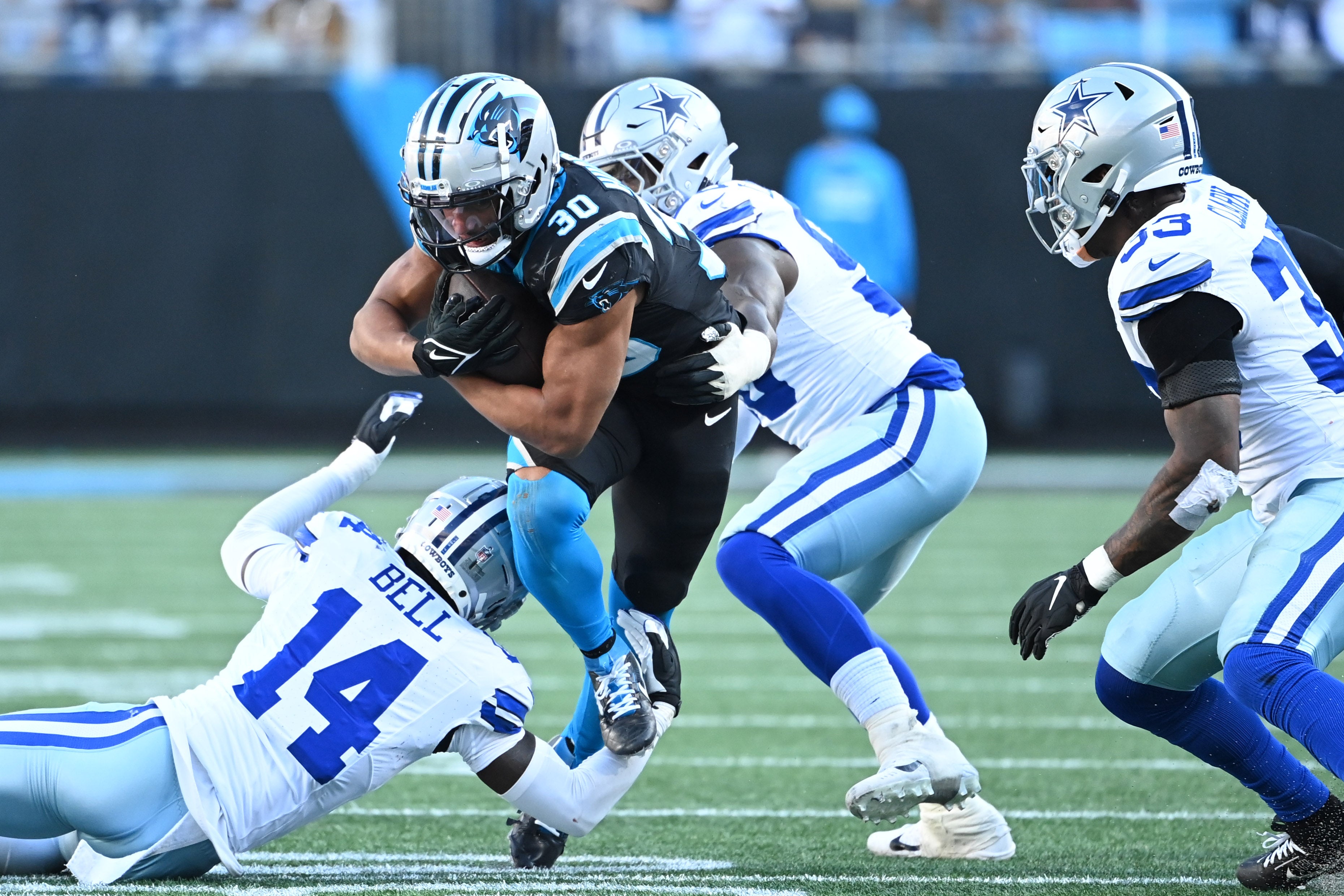 Carolina Panthers running back Chuba Hubbard (30) runs as Dallas Cowboys safety Markquese Bell (14) and defensive end DeMarcus Lawrence (90) and linebacker Damone Clark (33) in the third quarter at Bank of America Stadium.