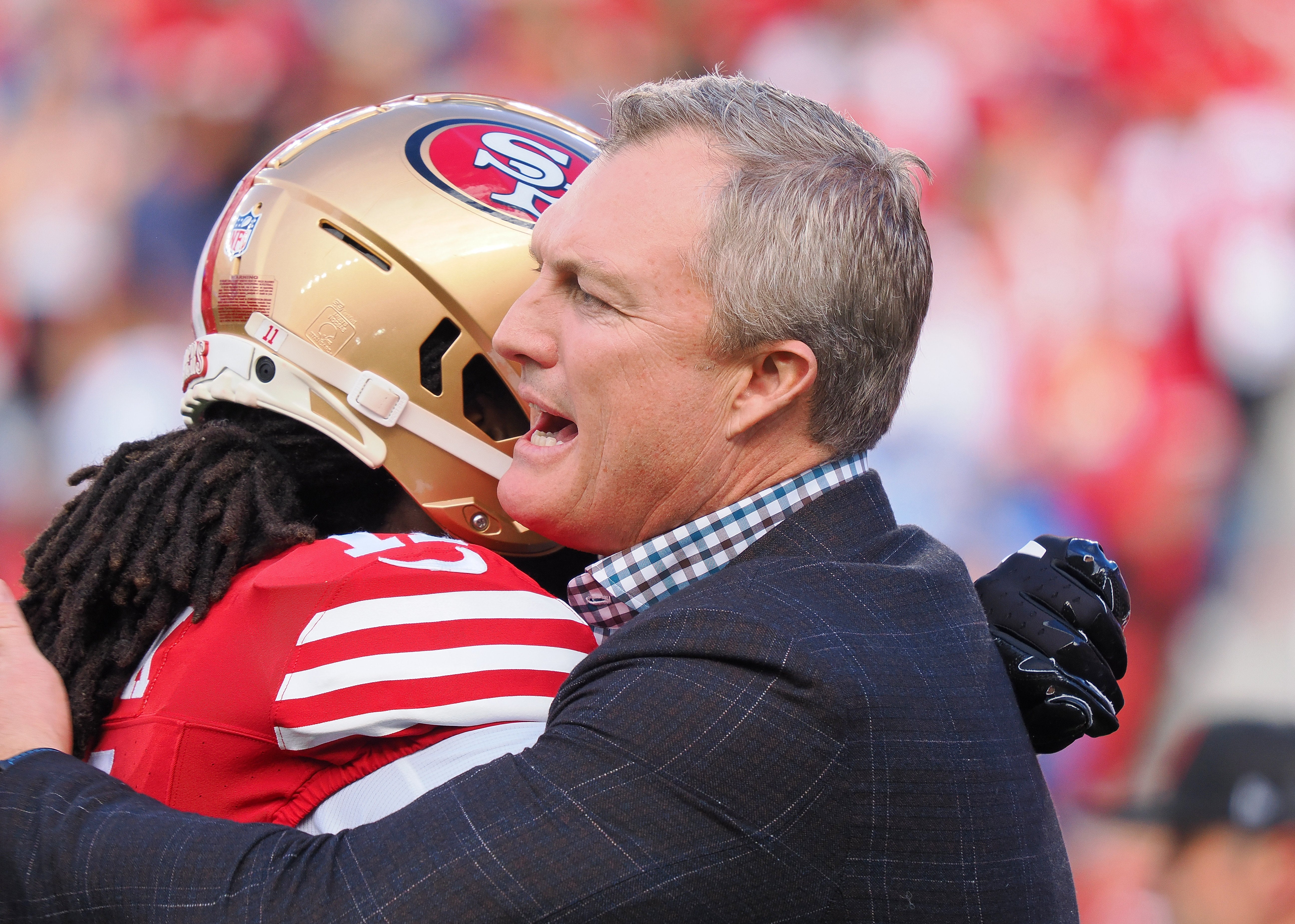 Jan 28, 2024; Santa Clara, California, USA; San Francisco 49ers general manager John Lynch hugs a player looks on before the NFC Championship football game against the Detroit Lions at Levi's Stadium.