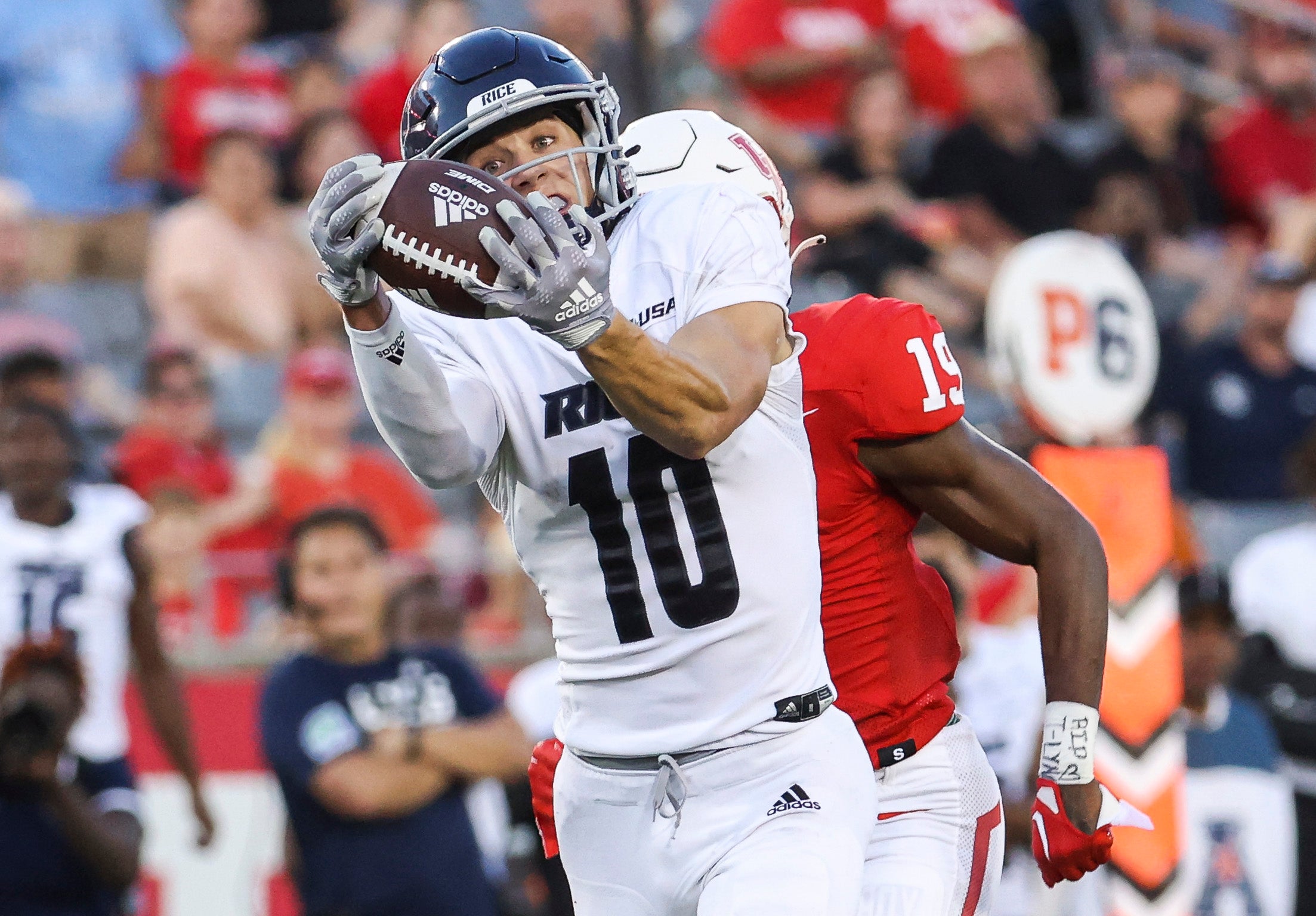 Sep 24, 2022; Houston, Texas, USA; Rice Owls wide receiver Luke McCaffrey (10) makes a reception and runs for a touchdown as Houston Cougars defensive back Alex Hogan (19) defends during the third quarter at TDECU Stadium.
